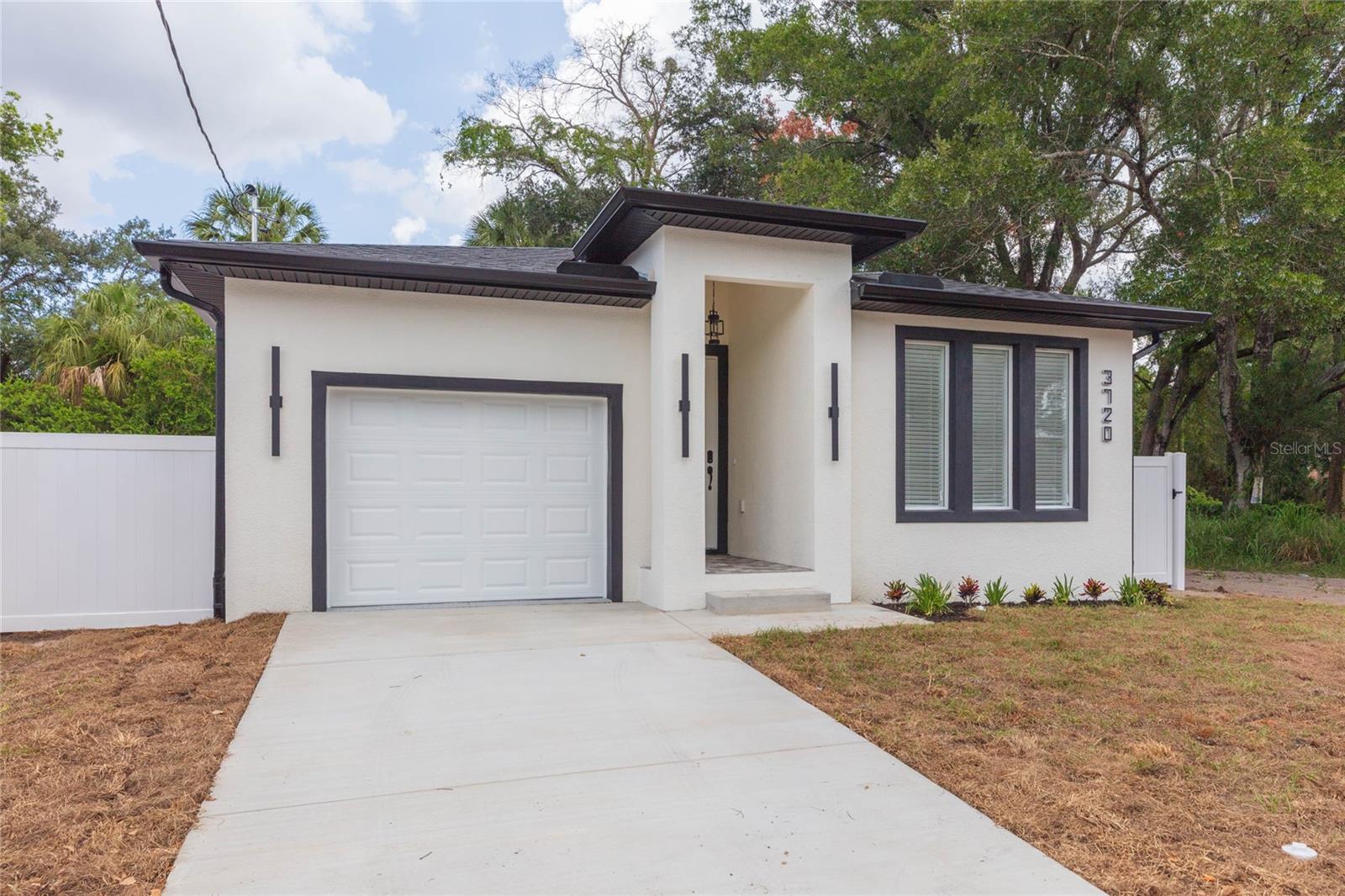 Prepare to be amazed by this ultra-modern, brand-new construction masterpiece in Tampa! Located at 3720 N 32nd St, this stunning 3-bedroom, 2-bathroom home boasts an eye-catching contemporary elevation featuring crisp white stucco paired with bold, dramatic black trim and sleek vertical lighting. Step through the frosted-glass front entry into a bright, light-filled interior showcasing pristine, large-format polished porcelain marble-look tile that flows seamlessly throughout the entire home.

The ultra-chic design continues into the bathrooms, highlighted by a gorgeous, custom marbleized accent wall in the shower, a sleek matte black vessel sink, an arched vanity mirror, and premium matte black hardware. Every bedroom features modern ceiling fans, crisp lines, and abundant natural light. Outside, enjoy complete privacy with a fully enclosed white vinyl fence and a pristine concrete driveway leading to your attached garage. With NO HOA or CDD restrictions and minutes from Downtown Tampa, Ybor City, and Armature Works, this turnkey architectural gem offers the ultimate urban lifestyle. Schedule your tour today!