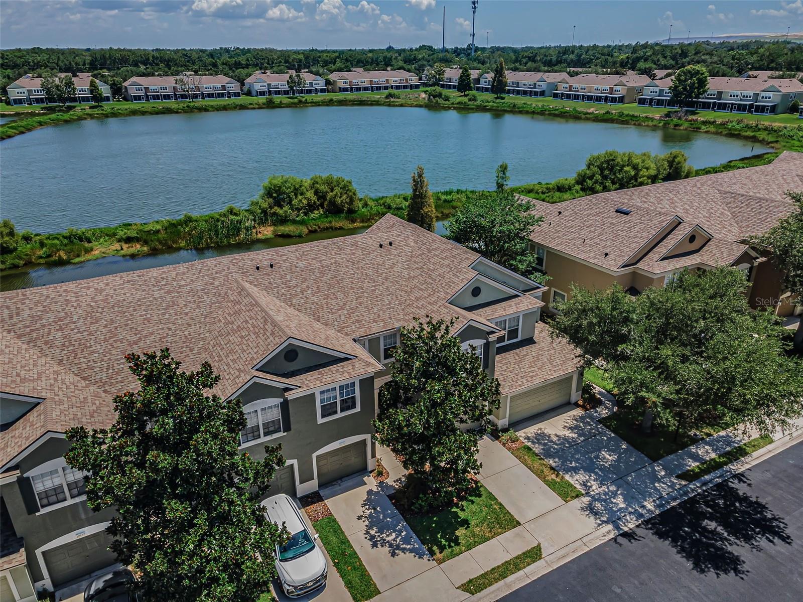 Water views and a contemporary, yet cozy interior welcome you to this stunning townhome that gleams with pride of ownership. The open-concept floor plan integrates an immaculate eat-in kitchen (complete with newer stainless-steel appliances and a glass-tiled back splash) with the adjacent dining and living rooms; both boasting gleaming hardwood flooring and stunning water views through the screened lanai, all revealed through a wall of sliders. Wonderfully light and bright, this 3 bedroom/2.5 bath/1 car garage townhome in the Valhalla subdivision is spacious and serene. The master bedroom with lovely ensuite includes a soaking tub/shower combo, dual sinks, and an enclosed commode room. A walk-in closet and water vistas through a triple window combine for a true retreat. An upstairs bedroom that currently serves as a home office is crowned with a vaulted ceiling and plenty of sunny square footage; ideal space to serve as anything from a private workout zone to a crafts room. The laundry room is outfitted with Whirlpool appliances/shelving, and the pantry offers handy storage, while the perfect powder room with pedestal sink, shines. A gated community, Valhalla boasts two spectacular community pools featuring a splendid, covered veranda and views of the sparkling lake. Reasonable HOA fees cover exterior maintenance/insurance, basic cable, internet, water, sewer, and trash service. New A/C as of 2022, Roof replaced 2023, Hot Water Heater in 2015. Along with easy access to I-75 as well as an abundance of local shops and great restaurants, a 30-minute drive gets you to Tampa International Airport and all the cultural hotspots of that ever-eclectic downtown.