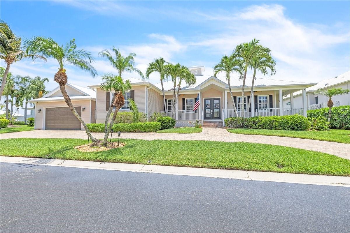 Discover an exceptional coastal retreat nestled within the highly sought-after gated community of Tidewater Island. This beautifully maintained 4-bedroom residence features two full bathrooms, two half bathrooms, and 2,449 square feet of thoughtfully designed living space that seamlessly blends elegance, comfort, and timeless Florida charm. The circular paver driveway leads to a spacious 2 car garage, while the classic metal roof accented by a decorative cupola and meticulously maintained grounds reflect true pride of ownership. Mature palms and curated landscaping provide both privacy and exceptional curb appeal, perfectly complementing the upscale character of this serene community. A charming front porch spans the width of the home, creating an inviting space to relax and enjoy the tranquil surroundings. Inside, the light-filled living room welcomes you with soaring tray ceilings, intricate crown molding, a statement chandelier, and elegant neutral tile flooring that create an atmosphere of understated luxury. Expansive windows and glass doors invite in abundant natural light, enhancing the home’s bright and airy feel. The thoughtfully designed floor plan flows effortlessly for both everyday living and entertaining and includes a formal dining room ideal for gatherings and special occasions. At the heart of the home, the beautifully appointed kitchen combines style, functionality, and craftsmanship. Crisp white cabinetry pairs seamlessly with elegant quartz countertops, while a contrasting wood-tone center island adds warmth, visual interest, and generous seating for casual dining. A custom wood range hood creates a striking focal point, complemented by pendant lighting, recessed lighting, high-end stainless-steel appliances, a built-in oven and microwave, and a modern tile backsplash. Open to the main living areas, the kitchen enhances the home’s spacious open-concept design. The well-appointed bedrooms provide comfort, privacy, and flexibility for family and guests alike. The owner’s suite features a refined coastal aesthetic with tray ceiling and French doors offer direct access to the outdoor living area, creating a seamless indoor-outdoor connection. The spacious en-suite bath includes a freestanding soaking tub, dual-sink vanity w/ quartz countertop, ample cabinetry, a large, framed mirror and a glass-enclosed walk-in shower with tile detailing, built-in bench seating, and both handheld and overhead fixtures. Additional bedrooms are thoughtfully positioned and can easily serve as guest accommodations, a home office, or creative space. Designed to embrace the Florida lifestyle, the home transitions seamlessly to the expansive screened lanai, where a heated in-ground pool and spa overlook peaceful lagoon and lake views. This inviting outdoor setting is perfect for relaxing mornings, entertaining guests, or enjoying breathtaking sunsets. Additional upgrades include plantation shutters, impact-resistant windows and front doors, an electric roll-down hurricane shutter on the lanai, and a functional laundry room for added convenience. Tidewater Island is an exclusive waterfront community celebrated for its quiet natural surroundings and distinctive Old Florida and Key West-inspired architecture. This intimate gated enclave offers privacy and charm while remaining conveniently close to downtown Fort Myers, Gulf beaches, shopping, dining, and entertainment. **PLEASE ENJOY THE 3D INTERACTIVE VIRTUAL TOUR ASSOCIATED WITH THIS LISTING**