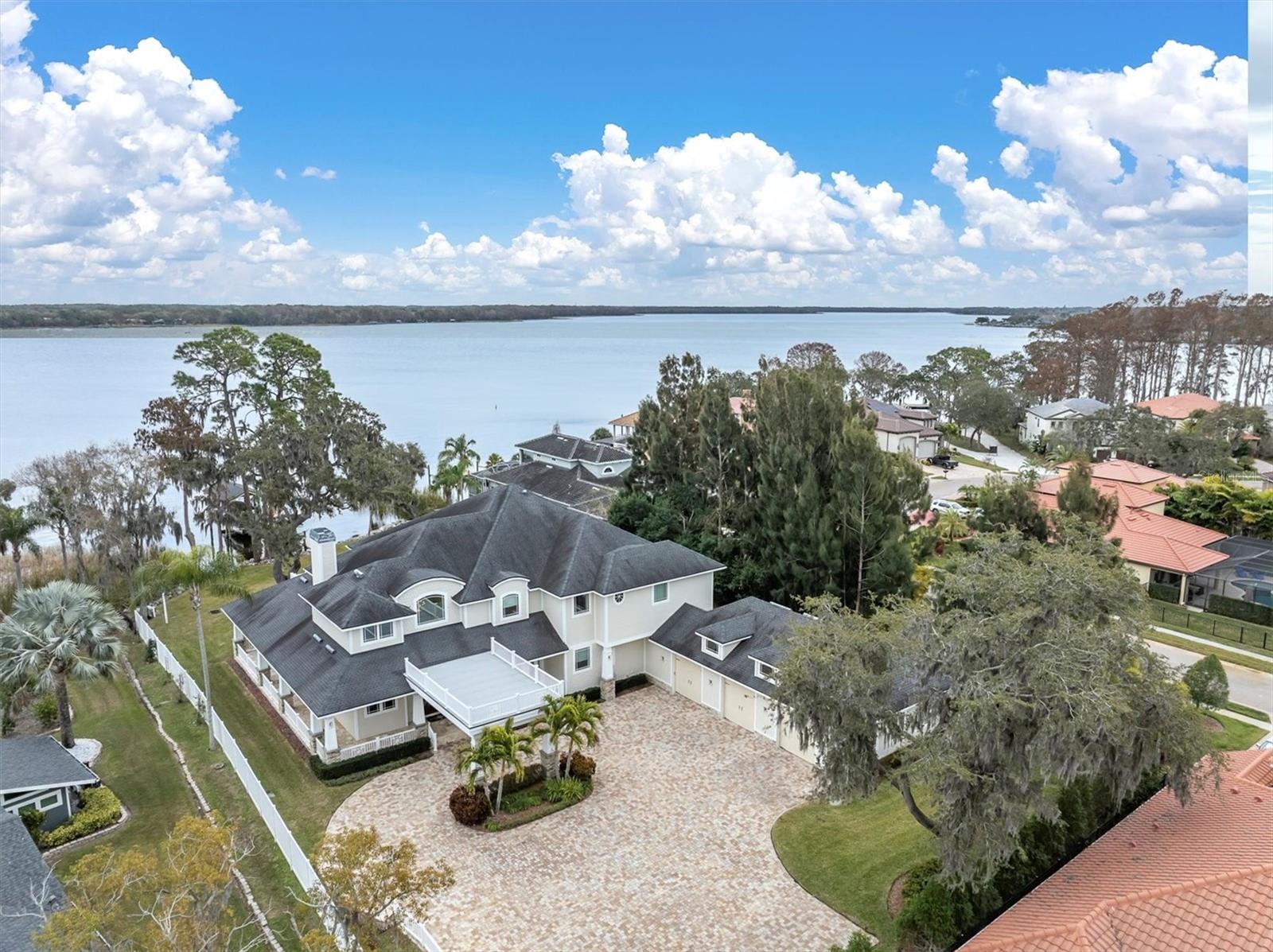 "PRICE ADJUSTMENT"    "Tucked away on a quiet and beautiful 1 acre lot on Lake Tarpon, this stunning residence offers magnificent water views from nearly every room with one of the most private entrances and lot in the area.  This newer home (6yrs) blends, charm and modern comfort, with the light filled rooms, open floor plan features begin upon entering by way of the Porte-cochere through custom designed double entry doors to a foyer with 20 foot soaring ceiling & retractable chandelier with piano alcove and light-filled conversation room featuring a fireplace to start the presentation of an absolutely stunning home. Craftsmanship is showcased throughout this home, from the millwork around all door openings, baseboards, coffered ceilings, to the 10 foot designer highlighted doors to each room, custom cabinetry in the kitchen, butler's pantry, bathrooms, game room and full sized & equipped laundry rooms. The combined family room, breakfast room and kitchen features coffered ceilings, spectacular views of the covered dock with lift, fire pit & seating overlooking the approximately 2600 acre Lake Tarpon as well as the sparkling open pool area featuring an outstanding gourmet outdoor kitchen for all those year round outdoor get togethers. In-home dining begins in the elegant dining room and becomes a reality in the Chef's dream kitchen with top of the line appliances, including Sub Zero refrigerator, GE Monogram gas range w pot filler, cabinet microwave and dishwasher encompassed by personally designed cabinetry with granite counters. Huge walk-in pantry accommodates all the necessary items needed to entertain guests and family for those spectacular parties to come. The owners suite features a morning coffee bar area with an adjacent reading room plus its own balcony with breathtaking views of the lake, private back yard and glistening pool area. The owner's bath is a fabulous place to spend the day, with all the accoutrements of a high end Spa! The owner's closets (2) are beyond comparable to any others with more than ample space for all personal belongings, shoe gallery & more. Family gatherings or parties of any kind can find their way to accommodate many guests in this beautifully appointed game room with pool table,  game table with large stock area bar. A 1000 bottle Wine Room constructed with concrete block walls with vapor barrier paint & insulation create a true wine room makes it a real treat for the wine connoisseur or collector. Each of the additional bedrooms have their own ensuite full bath with 2 of them having their own private balcony overlooking the beautiful lake. Finishing the day would be to enjoy a movie in your own 8 seat home theater just adjacent to the game room with additional insulation and soundproofing.  The 3 car oversized garage will accommodate oversized vehicles with driveway parking for a multitude of vehicle parking. The built-in staircase to the floored attic,  makes for easy storage of additional belongings & access. Outdoor features include a beautiful wraparound porch, lush landscaping (watered by lake), private paved, tree lined driveway, no HOA or fees for living the most enjoyable life possible. Safe Room constructed of reinforced concrete that affords safety and security.  The aforementioned description doesn't totally describe this beautiful and stunning home but seeing is believing. Come see to believe for yourself and be SOLD! Being in the heart of Palm Harbor close to everything."