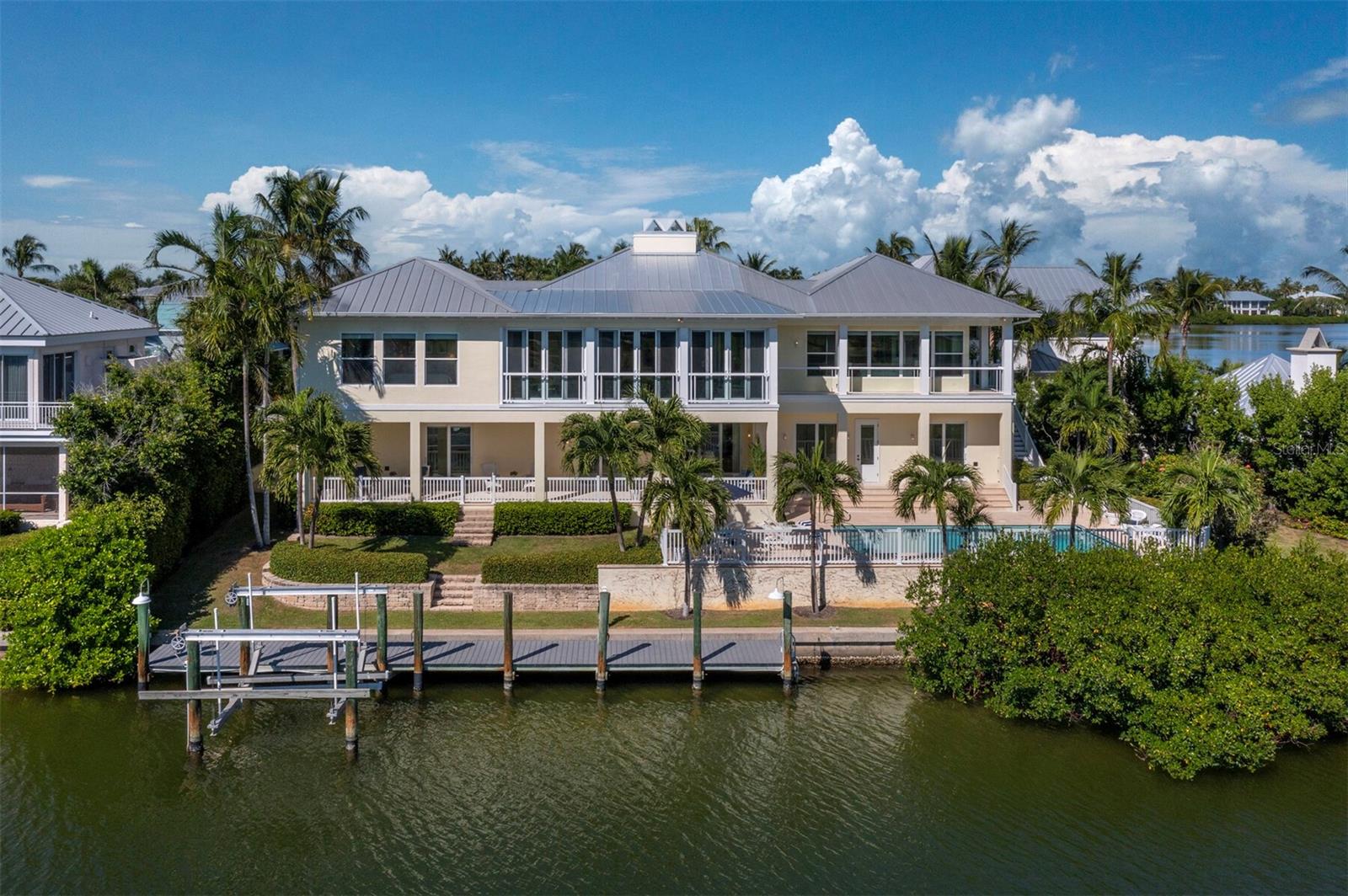 Under contract-accepting backup offers. Welcome to waterfront living at its finest in the exclusive gated community of Boca Grande Isles on Gasparilla Island. This stunning five-bedroom, five and one half-bathroom home sits on an impressive tip lot with 170 feet of deepwater frontage, offering expansive dockage with direct access to Charlotte Harbor and the Gulf with no bridges to navigate.  The southern exposure has breathtaking sunrise and sunset views from every room of Charlotte Harbor and the Gasparilla Inn Golf Course. 

Built with concrete construction for superior storm protection and impact glass windows and sliding doors throughout, this elevated 4,799 square foot home features an elevator and places the primary bedroom conveniently on the main living floor. The spacious primary suite includes a large bedroom with expansive water views, an office or workout room, and a spacious bathroom with dual vanities, dual closets, and dual water closets. The gourmet kitchen will make any chef smile with high-end appliances including a Subzero refrigerator, double ovens, induction cooktop, and ice maker. Granite countertops, an island, and breakfast bar complete this culinary paradise. Hardwood flooring flows throughout the home, while walls of glass in the living room and sunroom showcase those incredible water views. The large family room is the perfect spot to gather or entertain with multiple seating areas and a gas fireplace.  Your family and guests will appreciate the four ensuite guest rooms that share a cozy television room to ensure everyone has privacy and room to spread out. The spectacular outdoor living space at this home is where you will want to spend your time. There is a large, heated pool surrounded by multiple expansive patios and porches, palm trees and grassy areas, and a 50’ deep water dock with lift. Spend your days sunning by the pool or exploring the blue coastal waters.  An oversized two-car garage plus additional golf cart storage keeps your vehicles protected. 

Located in secure Boca Grande Isles with guard-gated access, you're just a short golf cart ride from the beautiful beaches of the Gulf or the charming shops and restaurants in Historic Boca Grande. The nearby Gasparilla Inn, Coral Creek private airport, multiple exceptional private and public golf courses, and local marinas all add to the island's appeal. This is coastal living done right.