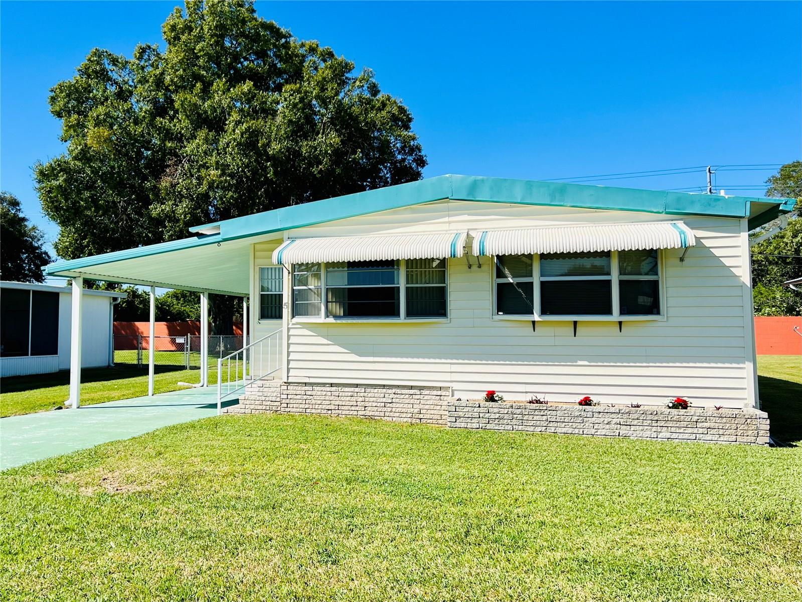 Looking for a 55+ mobile home in a retirement community to call home? Additionally, you OWN THE LAND, no lot rent! This must see, 2/2 doublewide is vacant & waiting for you! Walking up, you'll see an enclosed lanai with a wonderful space for enjoying a cup of coffee. It's open design allows for a refreshing and relaxed atmosphere, perfect for connecting with others or simply enjoying some peaceful moments. 
The interior of home has abundant natural lighting from windows, side door and sliding doors, creating a welcoming and comfortable living space. It's a great option for someone looking for a cozy yet spacious mobile home. Master bedroom has his & hers walk-in closet with en suite bathroom. The laundry room/workshop includes the washer & dryer. Home includes everything you see as well as appliances too. The back of the home has a beautiful large backyard, perfect for drying your clothes or sitting in the Florida Sun. Other features include outside gutters and newer windows throughout. This community has security from dusk till dawn. HOA is affordable and paid yearly. Amenities included; swimming pool, that is heated and cooled, rec room, shuffleboard, library/puzzle room and countless scheduled activities. Home rentals are allowed after one year. Boats, RVs and motorhomes are allowed under carports only. Don’t miss out and schedule your showing today!