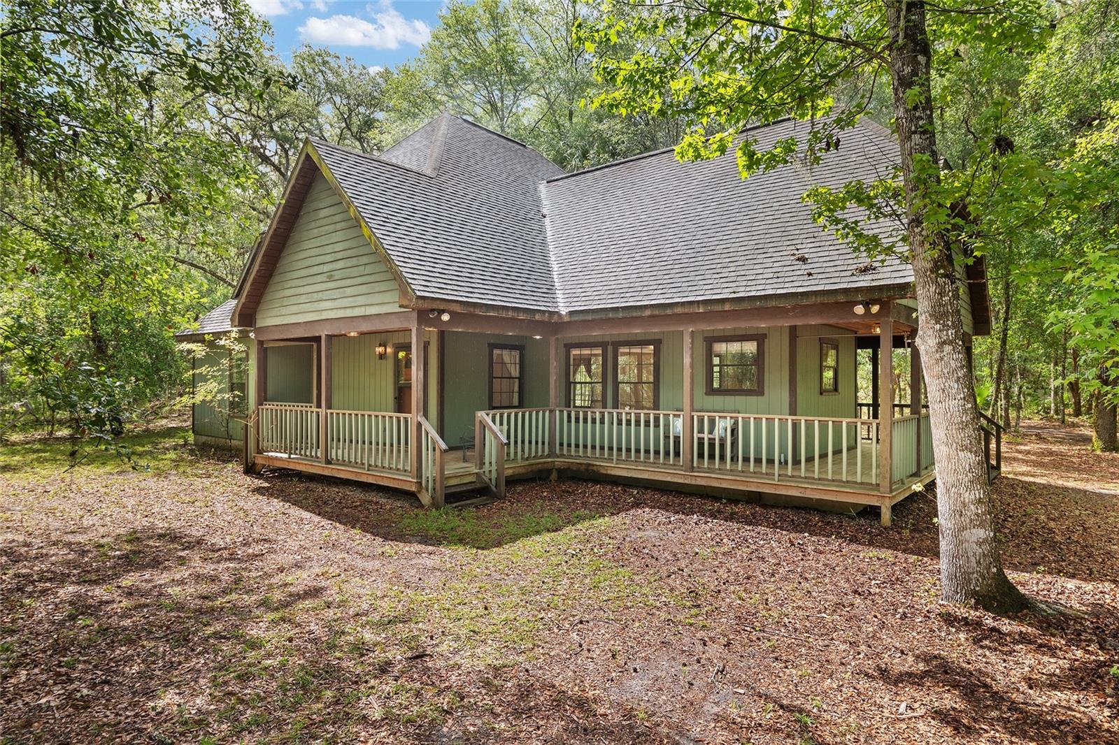 Step back in time to the pages of "A Land Remembered" and experience the timeless beauty of Old Florida. Travel beneath majestic oak trees and Spanish moss and discover this charming 3 bedroom 2 bath Cabin style home nestled on 7.14 private acres off CR 234. Full of rustic character, the home welcomes you with a classic wraparound porch, perfect for enjoying peaceful mornings and quiet evenings surrounded by nature. Inside, you'll find a home rich with charm and opportunity, ready for your personal touches and finishing details to make it truly your own. The vented attic room offers excellent potential for additional living space allowing you to customize it to fit your needs.  Major updates provide peace of mind, including 2 newer HVAC units and 2 newer water heaters. The oversized detached garage offers ample space for vehicles, storage or the workshop you've always wanted. Whether you're dreaming of a private country retreat or simply a place to enjoy the beauty of rural Florida, this unique property combines rustic charm, acreage and endless possibilities.