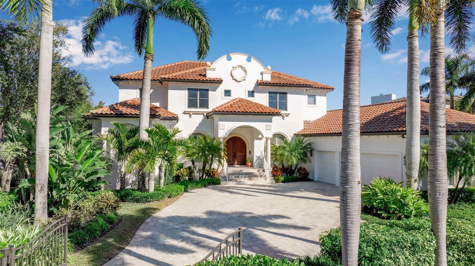 One or more photo(s) has been virtually staged. Step into a private, gated waterfront estate in Sarasota offering deep-water boating access, refined coastal architecture, and an unsurpassed location just minutes to Siesta Key Beach, Southside Village, and downtown Sarasota. Located in the coveted San Remo Estates community, this exceptional residence blends timeless elegance with modern functionality—perfect for buyers searching for a luxury Sarasota waterfront home with privacy and proximity to the city’s best dining, shopping, and beaches. Designed by renowned architect Walter Hamm and built by Bill McGinness, the home is engineered for lasting stability with construction supported by 54 concrete pilings, a powerful value point for buyers seeking a well-built coastal property. Set on a sprawling private lot with mature landscaping and serene surroundings, the home captures panoramic water views and features a protected deep-water harbor, ideal for boaters who want quick access to Sarasota Bay and Gulf. Inside, the home showcases a bright, open layout filled with natural light, elevated by custom millwork, coffered ceilings, rich wood flooring, and polished travertine. The gourmet kitchen is designed for both entertaining and everyday living, featuring an oversized center island, quartz countertops, premium wood cabinetry, granite perimeter counters, subway tile backsplash, and stainless-steel appliances, along with an inviting breakfast nook that overlooks the water. The adjacent family room creates a warm gathering space, while the formal dining room is ideal for hosting. A private office provides a quiet, dedicated workspace, ideal for today’s lifestyle. The primary suite on the main level is a true waterfront retreat with oversized windows framing tranquil views, two custom walk-in closets, and a spa-style bath with a floating vanity, illuminated mirrors, a freestanding soaking tub, and an oversized walk-in shower. Upstairs, the second level is designed for comfort and entertaining with three generous bedroom suites, a TV/game room, a convenient kitchenette, and a terrace that overlooks the pool and peaceful waterscape, perfect for guests, multi-generational living, or extended stays. Outdoor living is equally impressive, featuring an expansive travertine pool deck, a heated pool and spa, a fenced and spacious yard, and lush tropical landscaping that creates a resort-style environment with exceptional privacy. Andersen sliding doors and windows enhance the indoor-outdoor connection and raise the overall quality of the home. A comprehensive renovation completed in 2015 elevated the interiors with sophisticated, updated finishes, while key improvements include a new roof (2020) and updated AC systems (2023 & 2024). Additional features include an ADT security system, generous storage, abundant closet space, a large laundry room, provisions for an elevator, and an oversized three-car garage. Sought-after San Remo Estates is positioned at the heart of Sarasota, just before the north bridge to Siesta Key, making it one of the most desirable locations for those wanting a Sarasota luxury waterfront home with both convenience and privacy. This exceptional coastal estate delivers the ultimate Florida lifestyle: deep-water boating, serene water views, and effortless access to Sarasota’s beaches, culture, and world-class amenities.