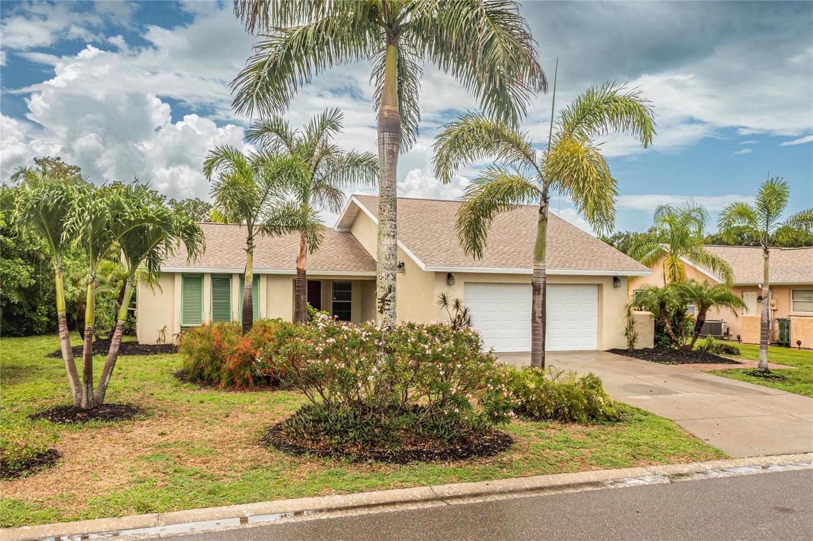 Seller is motivated! Bring all reasonable offers. Welcome to your Florida tropical paradise! This completely renovated home has an open floor plan, an island range/hood, quartz countertops, lush landscaping, paver walkways, and Bahamian shutters that set the stage for the level of ownership this home exudes! This move-in ready Village Green home is the ideal spot for your primary home, second home, or investment property. With soaring cathedral ceilings, this 2 bedroom/2 bath open floor plan has a great flow with its multiple living and dining spaces. Washing dishes has never been so calming with the peaceful water views from the well-appointed kitchen. The master bedroom retreat has sliders accessing the lanai and the back yard, and is equipped with ample closet space. The master bathroom has nice a vanity, beautiful ceramic tile, and an accessible walk-in shower. With lots of storage space and its own bathroom, the second bedroom makes a nice guest room or office. The oversized 2-car garage has epoxied floors and space for storage, tools, etc. The AC is 5 years old (2021). Please note: The irrigation system pulls from the lake water, saving money on your water bills. Also, HOA is optional. Book your appointment today!