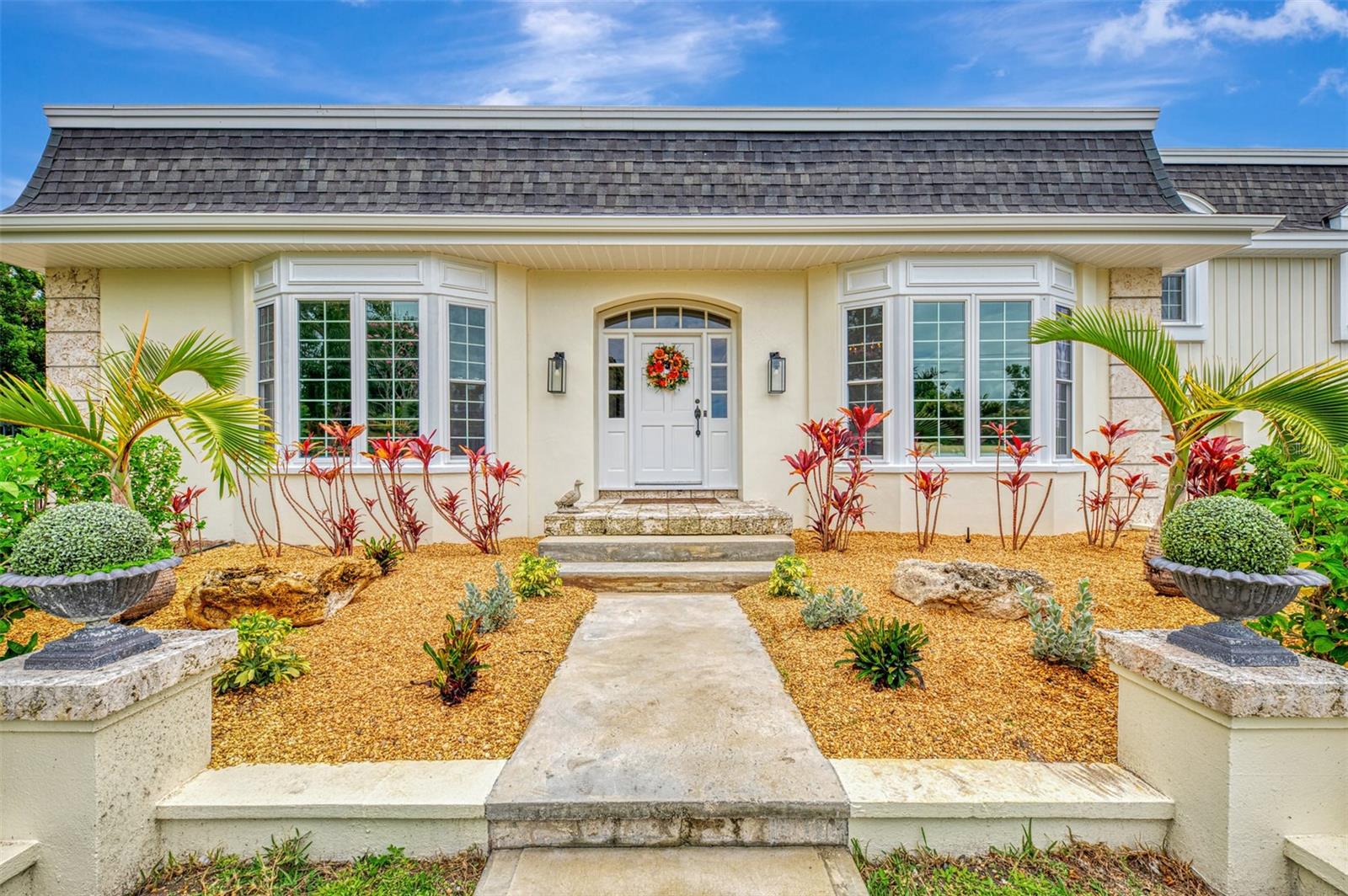 A rare opportunity to own one of the most distinctive homes overlooking Bradenton Country Club. Originally designed by renowned Tampa architect Harry MacEwen, this custom residence combines timeless architectural character with extensive modern upgrades and some of the most spectacular water and golf course views in the community. Designed to capture the scenery from nearly every room, the home features soaring volume ceilings, bay windows, wood flooring throughout much of the living space, a wood-burning fireplace, exposed beams, custom built-ins, abundant storage, and an inviting floor plan ideal for both everyday living and entertaining.
The heart of the home is a completely renovated chef's kitchen featuring dual ovens, dual dishwashers, a premium induction cooktop, and sweeping views of the pool, water, and golf course beyond. The spacious primary suite includes a beautifully remodeled bath, while the flexible second-floor layout offers additional bedrooms and living space ideal for guests, recreation, or work-from-home needs.
Outdoor living is equally impressive. An infinity-edge pool overlooks the tranquil water and fairways, complemented by an expansive travertine deck with multiple areas for dining, lounging, and entertaining. Aluminum and privacy fencing provide both security and seclusion.  The current owners have invested extensively in the property, including a new roof, impact-rated sliders and windows, major kitchen and bath renovations, HVAC replacement, siding replacement, updated irrigation, refreshed interior and exterior paint, upgraded bathrooms, and a redesigned circular driveway.  With its unique architectural pedigree, breathtaking views, and extensive list of recent improvements, this home offers a rare combination of character, comfort, and peace of mind in one of Bradenton's most desirable golf course settings.
Room Sizes are approximate and should be verified by the buyer.