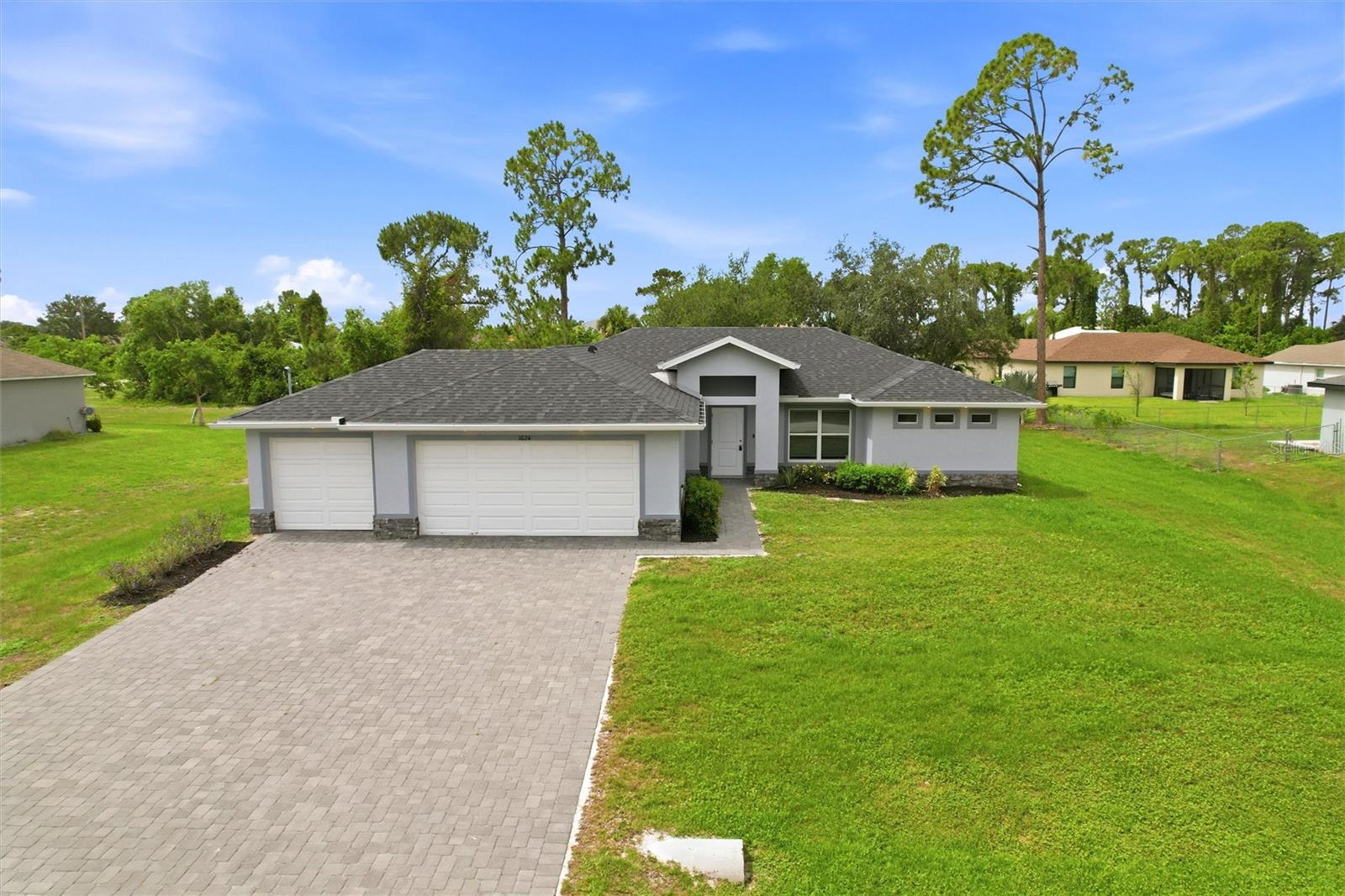 One or more photo(s) has been virtually staged. A clean, modern exterior sets the tone for this well-maintained 4-bedroom, 2-bath home built in 2021, offering 1,719 square feet of comfortable living space. The inviting façade showcases a crisp neutral color palette accented by attractive stacked stone detailing, adding texture and a touch of upscale appeal. A wide brick-paver driveway leads to the spacious THREE-car garage, while a covered front entry creates a warm and welcoming arrival. Thoughtful architectural elements, clean lines, and horizontal accent windows enhance curb appeal while allowing natural light to fill the interior. Inside, the open split floor plan provides both privacy and functionality, centered around a spacious great room that flows seamlessly into the dining area and kitchen—ideal for everyday living and entertaining. Tile flooring runs throughout the home, offering a cohesive aesthetic and easy maintenance. Sliding glass doors off the dining area open to a screened-in lanai, creating a seamless indoor-outdoor connection perfect for relaxing or hosting guests. The bright, modern kitchen is designed for both style and function, featuring an oversized granite island with seating for casual dining and entertaining. Coordinated gray shaker-style cabinetry provides ample storage and pairs beautifully with sleek stainless-steel appliances, including a range, microwave, and refrigerator. Recessed lighting enhances the contemporary feel, while the open layout keeps the kitchen fully connected to the main living spaces. Conveniently located off the kitchen, the laundry room with electric washer/dryer hookup and utility sink offers direct access to the three-car garage for added everyday convenience. The primary suite serves as a private retreat, highlighted by a dramatic tray ceiling and generous space. It features two closets, including a spacious walk-in closet. Spacious his and her vanities feature granite countertops, soft gray cabinetry, and abundant storage, all complemented by an oversized mirror and modern lighting. The impressive Roman-style walk-in shower is designed for both luxury and comfort, offering dual shower heads on opposite sides for a true his-and-hers experience. This expansive shower is beautifully finished with elegant tile, built-in recessed niches, and a sleek glass panels that enhance the open, airy feel. Guest bedrooms are generously sized with built-in closets and convenient access to a full bathroom, while the fourth bedroom offers versatile use as a den, home office, or additional living space. Surrounded by a neatly maintained lawn and simple landscaping, this property offers a fresh, open feel with plenty of room to personalize. Blending modern finishes with everyday functionality, this home delivers a polished and inviting first impression. Conveniently located in Northeast Cape Coral with easy access to Pine Island Road and Del Prado Boulevard, offering quick connections to shopping, dining, schools, and medical facilities. Just a short drive to North Fort Myers, I-75, and downtown Fort Myers, making commuting and daily errands simple and efficient. Situated in a growing residential area surrounded by newer homes and quiet neighborhood streets. ***PLEASE ENJOY THE 3D INTERACTIVE VIRTUAL TOUR ASSOCIATED WITH THIS LISTING**