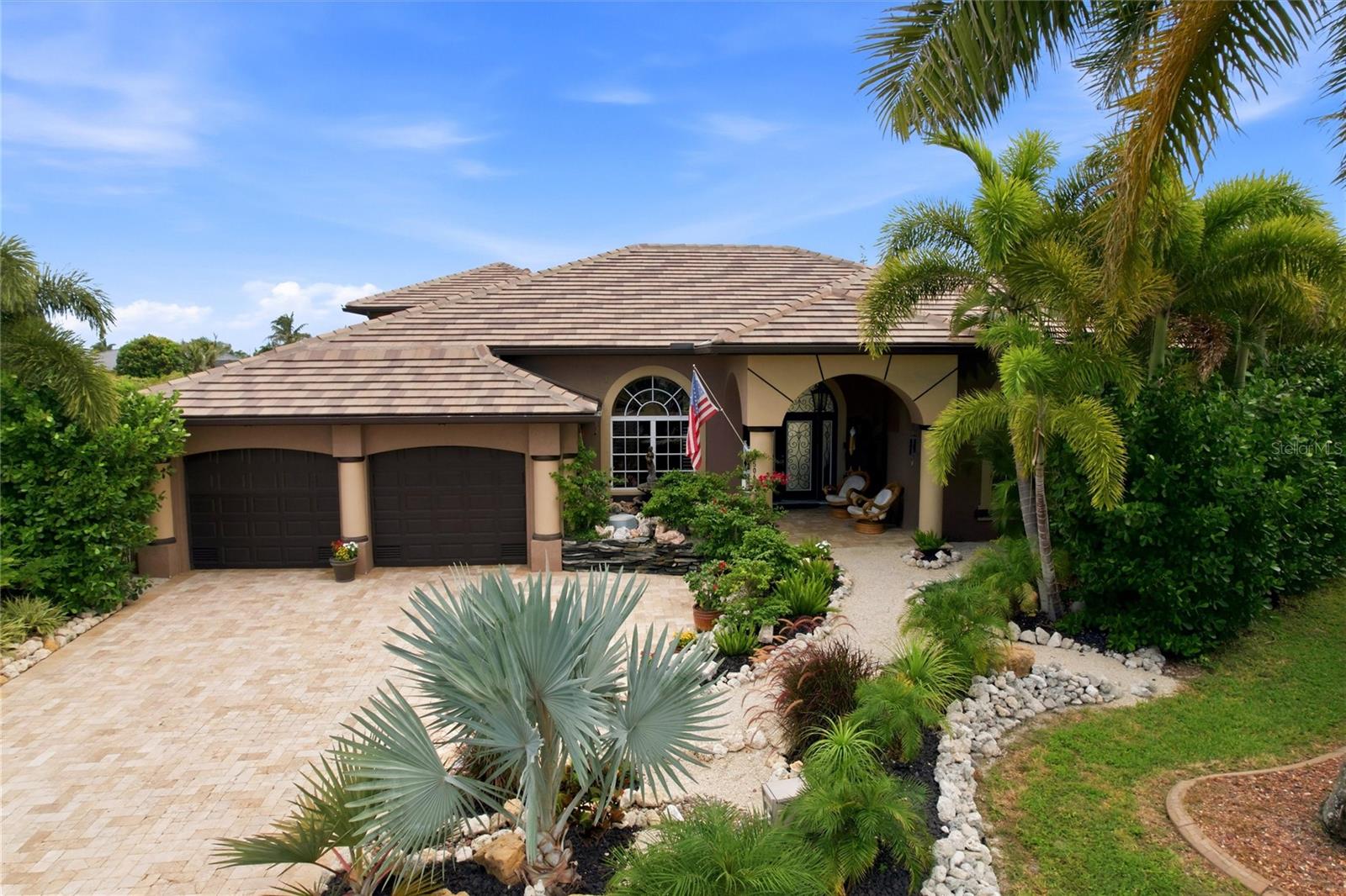 Completely remodeled, this stunning Fero Construction–built waterfront pool home offers an exceptional living experience in the highly sought-after community of Burnt Store Isles. Featuring 3,540 square feet of thoughtfully designed space, this impressive residence includes 4 spacious bedroom suites, 4.5 bathrooms, and a three-car garage, all perfectly positioned on an oversized tip lot with 169' of canal frontage. From the moment you arrive, the home makes a striking impression. A wide paver driveway leads to meticulously landscaped grounds with mature palms, lush tropical greenery, and decorative stone accents, creating outstanding curb appeal. A private courtyard-style entrance sets the tone, highlighted by a tranquil pond with a cascading water feature, natural stone finishes, and artisan details. Inside, the great room serves as the heart of the home. Soaring ceilings and an open-concept layout create an airy, inviting atmosphere, seamlessly connecting the living, dining, and kitchen areas—ideal for both everyday living and entertaining. Expansive sliding glass doors bring in abundant natural light and open fully to the lanai, pool, and stunning waterfront views. The gourmet kitchen is both beautiful and functional, featuring custom cabinetry that extends to the ceiling, sleek granite countertops, and a designer tile backsplash. A large center island with bar seating provides the perfect gathering space, complemented by high-end stainless-steel appliances, including built-in wall ovens. A tray ceiling with modern lighting adds architectural interest, while the open layout keeps you connected to the living spaces and expansive water views. The primary suite offers a spacious retreat with room for a full furniture set. A tray ceiling adds dimension, while large windows with plantation shutters fill the space with natural light. A custom feature wall with built-in shelving and media storage creates a focal point, and the layout easily accommodates a sitting area. Walk-in closets provide generous storage and organization. The en-suite bathroom is well-appointed with dual vanities, granite countertops, custom cabinetry, and vessel sinks. A soaking tub sits beneath a glass block window for privacy and natural light, while the walk-in shower features floor-to-ceiling tile, accent detailing, and a rainfall showerhead. A versatile bonus room offers flexibility as a home office, media room, or additional bedroom. Featuring custom live-edge woodwork, rustic accents, and a wood plank feature wall, the space blends style and functionality. Three additional guest bedrooms each include their own private bathrooms, providing comfort and convenience for family and visitors. Step outside to your private waterfront oasis. The covered lanai overlooks a sparkling heated saltwater pool with spa and tranquil waterway, offering the perfect setting to relax or entertain.  One of the property’s most exceptional features is its extensive waterfront, with a cement dock and 20,000-pound boat lift providing sailboat access to Charlotte Harbor. This custom residence showcases impeccable design, high-end finishes, and thoughtful attention to detail throughout. From its elegant interiors to its breathtaking outdoor spaces, every element has been carefully curated to create a home that is both luxurious and inviting. Don’t miss this opportunity to own a remarkable waterfront retreat where every day feels like a vacation.