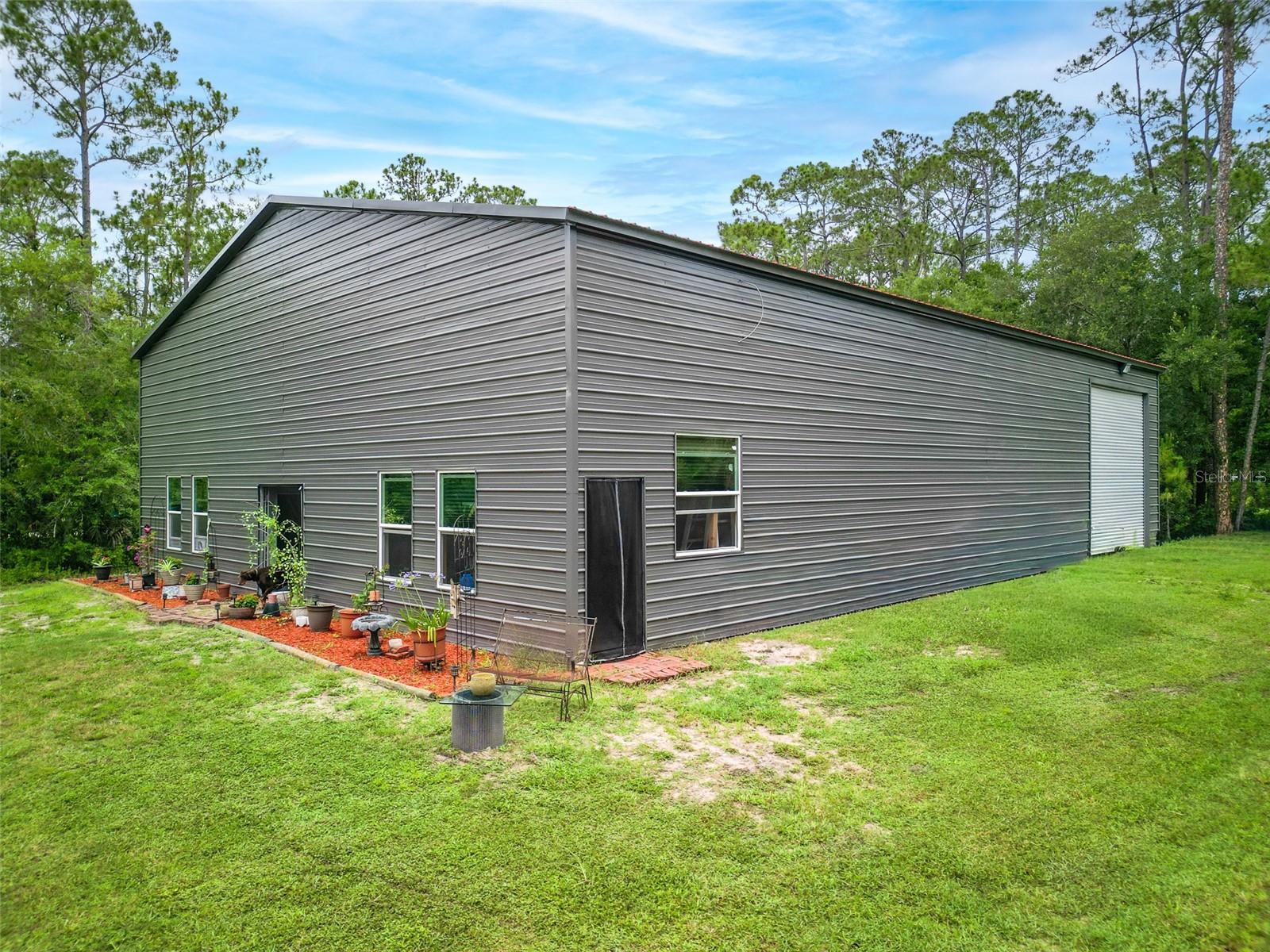 Unique opportunity on 5 private acres in New Smyrna Beach featuring a 50' x 70' steel building with 16' sidewalls, a 23' peak height, and pull-through 14' roll-up doors. Ideal for contractors, landscapers, RV owners, hobbyists, or anyone needing substantial workspace and storage. Permits have been obtained and approved, with rough-in and framing inspections already completed. A portion of the building has been framed for future living space, providing a valuable head start for the next owner. The project remains unfinished, offering the flexibility to complete it to your own specifications and needs. Access from both Western Road and Canal Road provides excellent functionality for equipment, trailers, and business operations. Whether you're looking to create a custom barndominium, operate a business from home, store recreational vehicles and equipment, or build a private country retreat, this property offers exceptional potential. Enjoy the peace and privacy of rural living while remaining just minutes from shopping, dining, and everything New Smyrna Beach. All information deemed reliable but not guaranteed; buyer to verify.