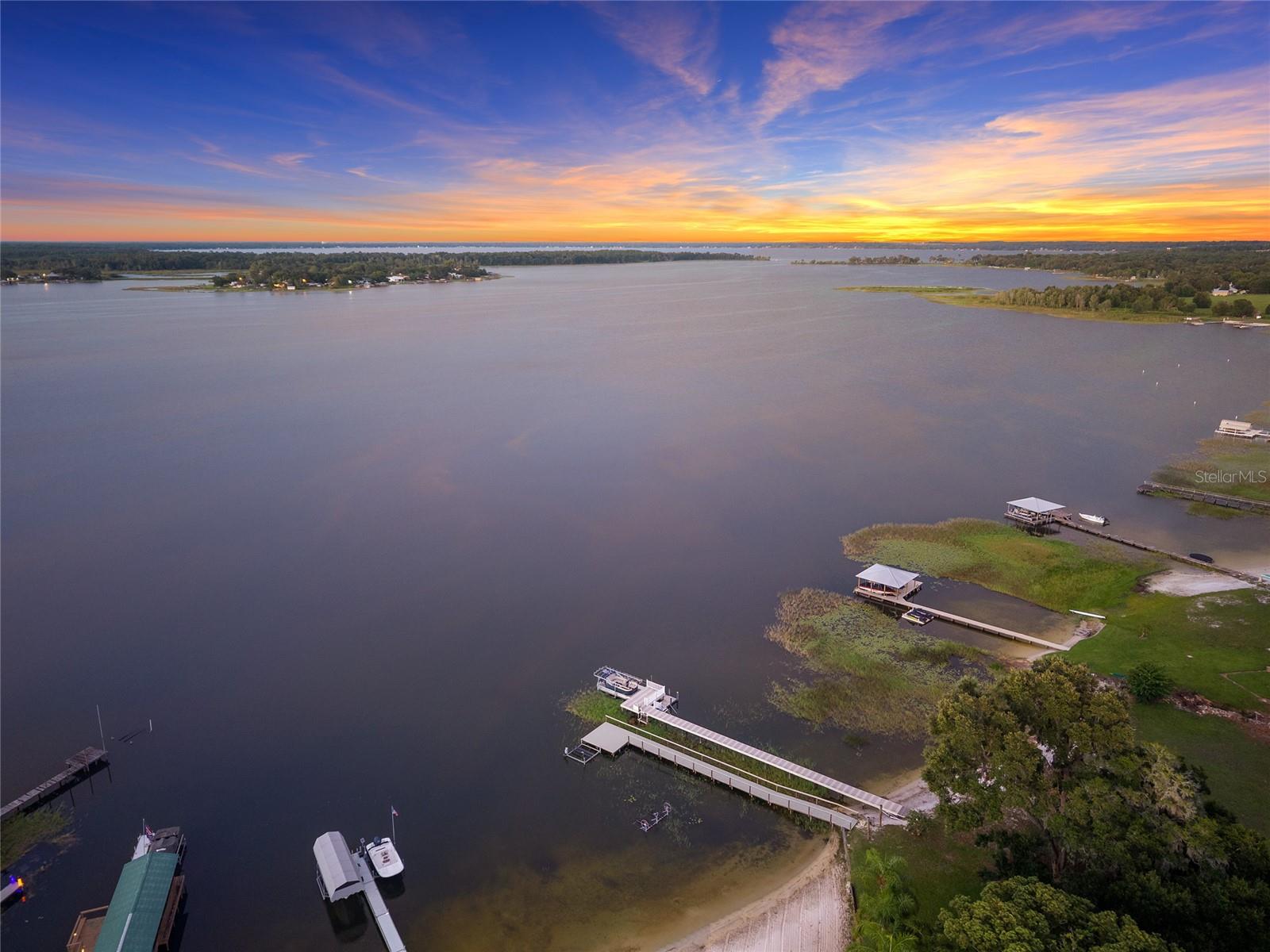 Rare Lake Weir Waterfront Compound | Acreage + Sandy Beach | Minutes to Ocala & The Villages

Discover a truly one-of-a-kind lakefront retreat on Lake Weir, offering the perfect blend of privacy, space, and Florida resort-style living. Set on 3.44 acres with 147 feet of pristine sandy beachfront, this gated waterfront estate delivers the rare opportunity to own acreage directly on the water—ideal for buyers relocating to Florida in search of sunshine, serenity, and year-round outdoor living.

Surrounded by mature trees, lush landscaping, and peaceful water views, the property is designed as a private family compound or vacation retreat, featuring two fully furnished lake homes plus expansive guest accommodations. The residences include a charming 2-bedroom, 1-bath home and a second 2-bedroom, 2-bath home with an attached garage, offering flexibility for multi-generational living, hosting guests, or income potential.

A standout feature is the climate-controlled guest quarters above the four-car garage, currently used as a flex and game space, complete with tall ceilings, a wood-burning/gas fireplace, and a full bathroom—perfect for entertaining, extended stays, or creative use.

The outdoor experience is unmatched, with a private dock, sandy swim beach, paved drive, RV carport, extensive concrete walkways, and multiple gathering areas to enjoy sunrise coffee or sunset views over the lake. This is true Florida lakefront living, where boating, swimming, fishing, and watersports become part of everyday life.

Located just minutes from shopping, dining, and entertainment in The Villages and Ocala, and a short drive to the World Equestrian Center, this Lake Weir estate offers both convenience and tranquility. For those seeking a quiet waterfront lifestyle with easy access to modern amenities, this property delivers the best of both worlds.

All homes convey fully furnished, making this a seamless move-in opportunity. Select recreational items—including a ski boat, Jet Ski, ATV, trailer, and water toys—may be negotiated separately.

Whether envisioned as a primary residence, second home, multi-generational estate, or investment retreat, this exceptional Lake Weir waterfront compound is a rare offering in Marion County.

Schedule your private showing today and experience the serenity, space, and sunshine of Lake Weir living.