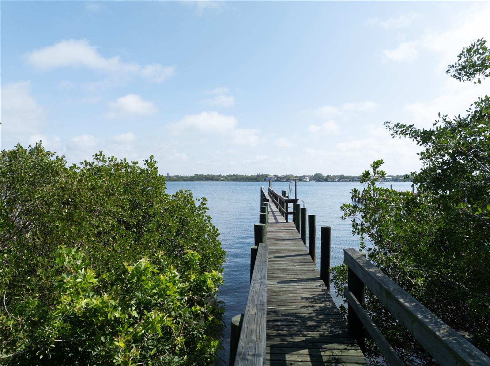 Seller Will consider All Offers!
This rare to find a 1-acre flag lot extends down to the Little Sarasota Bay waterfront in one of the most desirable locales on the sandy barrier island of Siesta Key, across the street from the prestigious Sanderling Club. Imagine a canopied driveway leading to your secluded dream home, with immediate access to all that Siesta Key and the emerald green waters of the Gulf of Mexico and the Intercoastal Waterway have to offer. You will enjoy your personal gateway to endless aquatic adventures, including boating, fishing, kayaking, paddleboarding, and shelling, or just relaxing on the beach. Stroll to your private dock extending approximately 235 feet into the bay waters, capable of docking a boat, jet skis, and kayaks. Walk or cycle 0.3 miles to the limited access Point of Rocks beach, a unique snorkeling and scuba diving spot, at the southern end of the world-renowned Siesta Key Beach, famous for its powdery white sands and calm, crystal clear waters. The Key’s South Village, adjacent to the island’s south bridge to the mainland, is a mere 0.7 miles from your front door. In addition to Siesta Key’s best beach bars, South Village has a shopping area, grocery store, restaurants, fish market, and beach rentals, as well as a Marina, where your recreational boating needs abound. You won’t want to leave your new digs, but there is a lot more to this area. A tropical paradise married to a clean, vibrant city with a historic downtown is a rare combination, but it’s yours, only 7 miles up the coast in Sarasota, making it the epitome of Florida’s Sun Coast living! In addition to its charming feel, Sarasota boasts a world-class Arts and Entertainment scene, with an array of upscale shops, gourmet restaurants, and vibrant nightlife venues to lure you out of your beach home for a “night on the town.” Indulge in a performance of a classic opera at the internationally acclaimed Sarasota Opera House, or catch a live blues show in a waterfront bar. Come claim your piece of Paradise!  DRONE VIDEO ATTACHED TO THE LISTING!  ***Also being offered as a land home package at MLS# A4622370***
