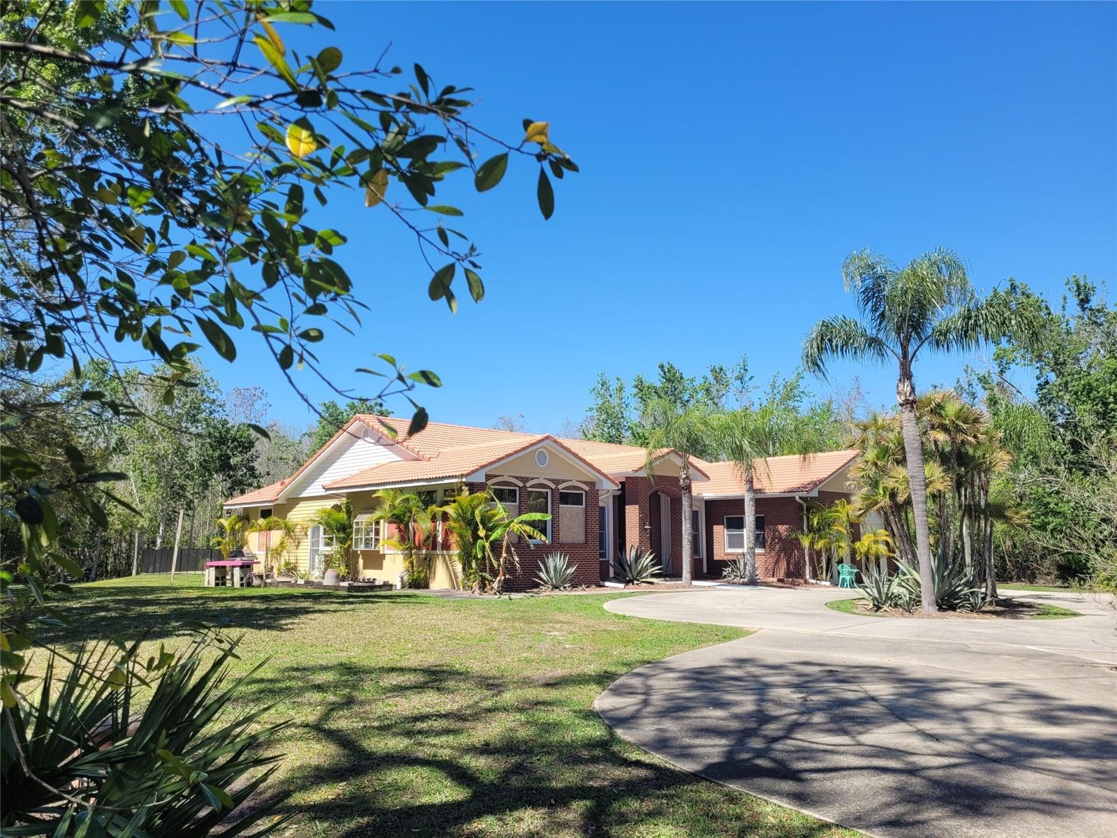 This elegant estate home is located in Kissimmee with close proximity to Central Florida business and Orlando communities with an astounding 5.47 total acres of land surrounding the actually developed almost 2 acres. This is privacy and land at an affordable price. The breathtaking tree-lined private drive creates eager anticipation for the primary residence. This is a compound for the large family or extended family. Not to be disappointed, you are welcomed via a circular driveway entrance with abundant parking for the family with multiple automobiles or guest parking. You enter through the beautiful double mahogany door to the stunning home with large open rooms including, foyer, dining, den, oversized pool, and tremendous fourth bedroom or game room. The kitchen is equipped with high-end appliances and gorgeous wood cabinetry. The additional 1 bedroom 1 bath detached guesthouse with kitchenette overlooks the stunning wooded and greenbelt views. This home has million dollar-type upgrades at a very affordable price. 3 a/c systems, radio/intercom system throughout, Anderson windows are double paned and insulated, lush landscaping, tiled roof, outside screened lanai with views of a magnificent natural wooded landscape. Additional amenities are 10-12 foot ceilings, crown molding, dual water heaters,  fully tiled home, new skylights, remodeled laundry room, new stainless steel oven, dishwasher, refrigerator, custom blinds, RV electrical hookup by garage/guest apartment. Gorgeous, private retreat.