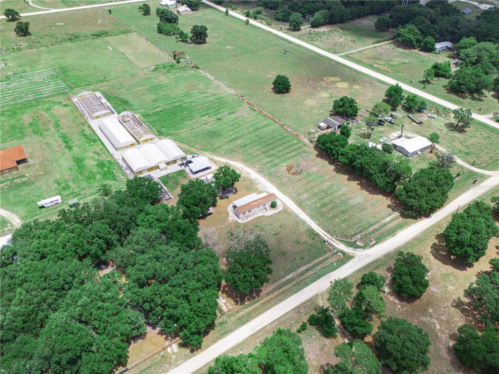 Turnkey opportunity to own 5 acres of improved agricultural land with existing nursery infrastructure! This versatile property is currently functioning as a citrus nursery, with the infrastructure already in place to support expansion into a variety of other agricultural uses. Featuring four greenhouses (one greenhouse has 3 domes) totaling in approximately 16,000 square feet, each equipped with electricity and water. This property has two 4-inch wells with 5-inch submersible pumps, fertilizer injectors, a commercial-grade chemical/fertilizer sprayer, overhead irrigation, greenhouse benches, 150,000 citrus grow pots, and much much more. Everything you need to hit the ground running. There is additional space for in-ground planting, that has an existing irrigation system with timer already installed. On-site structures include a 12x12 air-conditioned office shed, a 8x8 dedicated chemical storage shed, and a 16x20 workshop with an attached lean-to for additional workspace and storage. Also included is a 2006 single-wide mobile home offering 2 bedrooms and 2 bathrooms, with a split floor plan. The home features a rear covered porch, a private storage shed, and a full-home water purification system that also services the workshop and ice machine. Perfect for on-site living or staff housing. This property is fully set up and ready for continued operation. All measurements to be verified by buyer.