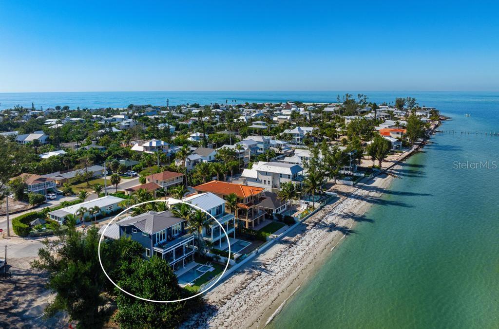 DIRECT BEACHFRONT - Positioned on the pristine shores of Anna Maria Island, this extraordinary direct beachfront estate offers a rare opportunity to own a luxury coastal retreat while building lasting generational wealth through an exceptional income-producing opportunity. Offered turnkey furnished, this stunning residence seamlessly combines refined beachfront living with an impressive history of high-performing short-term rental revenue. Thoughtfully updated with numerous recent enhancements—including new upper-level sliding glass doors—this home is designed to maximize breathtaking panoramic views of Tampa Bay and the iconic Sunshine Skyway Bridge. Expansive walls of glass flood the open-concept living and dining spaces with natural light, while floor-to-ceiling sliders lead to a spacious waterfront balcony, creating the perfect setting for entertaining or simply enjoying the serenity of the Gulf Coast lifestyle. The gourmet kitchen is beautifully appointed with shaker-style cabinetry, quartz countertops, an oversized island with seating, and premium stainless-steel appliances, including a gas range. Each of the four spacious bedroom suites serves as a private retreat, complete with its own en-suite bath and private balcony surrounded by lush tropical scenery.  Additional upgrades include refreshed tropical landscaping with exterior lighting, new ground-level outdoor furnishings, and freshly painted interior and exterior spaces. The covered poolside lounge and dining area provide the ultimate waterfront experience, just steps from the sugar-sand beaches of Anna Maria Island. In the evenings, unwind as the illuminated Skyway Bridge creates a spectacular backdrop across the bay. Beyond its timeless coastal architecture and unmatched beachfront setting, this property presents a truly remarkable investment opportunity with a proven track record and substantial rental income. The residence generated nearly $500,000 in projected income for 2025, with $456,000 booked in 2024 and $464,000 in 2023. Future reservations for 2026--2027 are already in place, offering immediate continuity of revenue and long-term wealth-building potential. Comprehensive rental history and future booking details for 2025 and 2026 are available upon request.  A rare offering that blends luxury, lifestyle, and legacy investment potential—this is beachfront ownership at its finest.