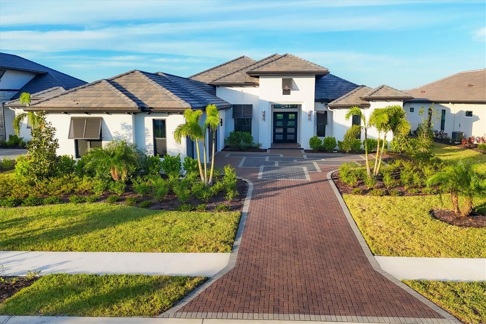 Welcome to this stunning, newly constructed 3,219-square-foot Rutenberg Talise model home, offering breathtaking water views in the Wild Blue at Waterside community. This luxurious residence features three spacious bedrooms, three and a half beautifully appointed baths, a den and a versatile bonus room. At the heart of the home is a breathtaking chef’s kitchen, complete with Thermador appliances, sleek quartz countertops and beautiful wood cabinets. This space opens seamlessly to the great room and dining areas, creating an ideal setting for entertaining and everyday living in the home’s open layout. Architectural details, including crown molding and tray ceilings, combined with beautiful wood floors enhance the warmth and elegance throughout the home. The professionally designed office boasts beautiful wood floors and is enclosed by elegant glass-insert sliding doors, offering both privacy and style. Whether you work from home or need a quiet space to focus, this office combines functionality with sophisticated design. The oversized bonus room is a flexible space that can be used as a second entertainment room, game room or additional living area. With 11-foot ceilings and plenty of natural light, it offers a spacious, airy feel. The bonus room is conveniently near a powder room, which also doubles as a pool bath, providing easy access from the outdoor living area. For the ultimate indoor-outdoor living experience, corner sliders open to the lanai, inviting you to step outside and enjoy Florida’s year-round sunshine in your private outdoor oasis. The backyard features a pool, relaxing spa and a spacious lanai including an outdoor kitchen with a grill, making this outdoor area a perfect place for relaxing or hosting guests. The luxurious owner’s suite offers a peaceful retreat with dual walk-in closets and a spa-like bath, complete with a soaking tub, walk-in shower and dual vanities. Two additional guest bedrooms, each with their own en-suite baths, provide comfort and privacy for family and visitors. A three-car garage offers ample storage and convenience. In the prestigious Lakewood Ranch area, Waterside is the pinnacle of luxury lakefront living. This planned community surrounds you with natural beauty, featuring sparkling lakes, lush landscapes and thoughtfully designed neighborhoods. With landscaping maintenance included, you’ll have more time to enjoy the resort-style amenities, including parks, walking trails, a village spa, tennis and pickleball courts, dog parks, playgrounds, golf and clubhouses. The vibrant town center offers boutique shopping, dining and entertainment just minutes away. Don’t miss the opportunity to make this extraordinary home yours and experience the best of luxury living at Wild Blue at Waterside.