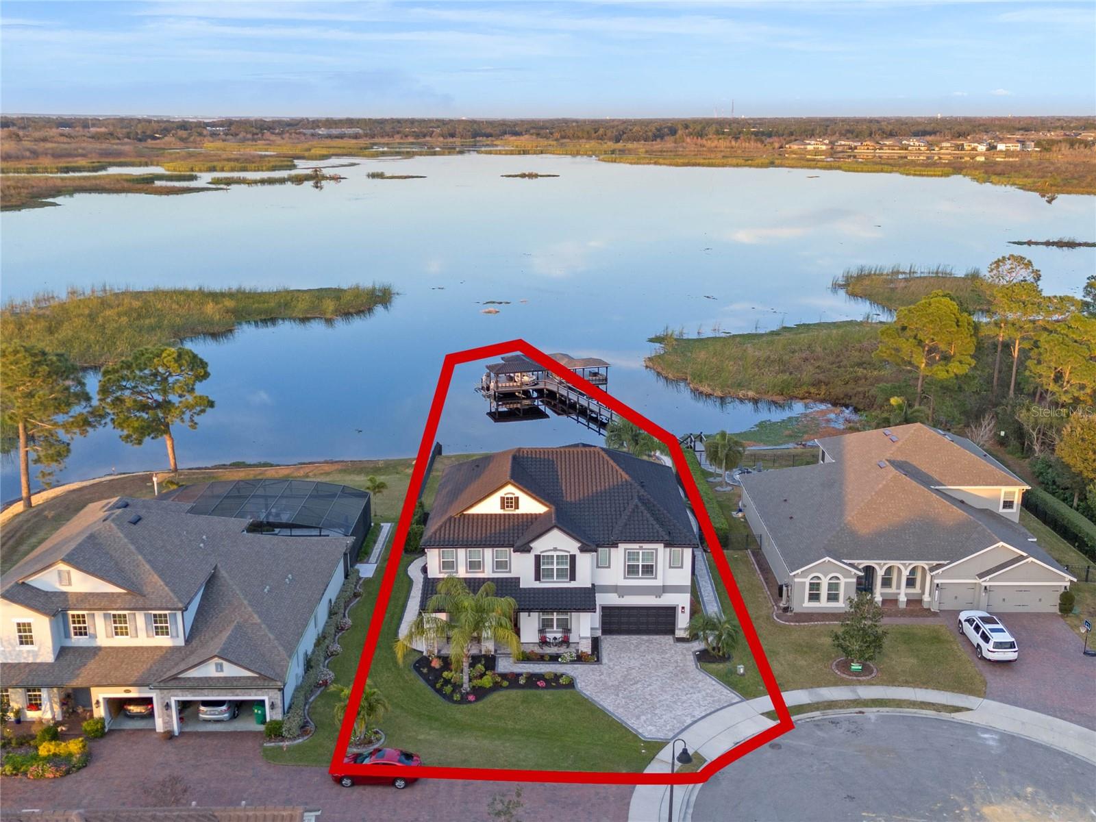 Exclusive Lakefront Luxury Home in Winter Garden! Nestled on Emerald Pointe, Hickory Hammock’s own Private Island, this exceptional property offers Breathtaking Panoramic Water Views of Johns Lake and an Array of Luxury Features. Enjoy your Private Boat Dock, Saltwater Pool and Spa, a Fully Equipped Outdoor Kitchen, Wood Burning Fireplace, and a Spacious Fenced Yard with a Professionally Designed Putting Green—perfect for outdoor entertaining. Upon entering this exquisite home from the welcoming front porch, you are greeted by an inviting and thoughtfully designed interior. The Main Floor features a Formal Dining Room, a versatile Office/Living Room, and a sophisticated Wine Room. The expansive Great Room offers an Open-Concept Layout with a Gourmet Kitchen, showcasing 2-inch thick Quartz Countertops complemented by a Large Island with a Waterfall Edge and White Shaker Cabinets complemented by sophisticated upper glass-front cabinetry. This space also includes a Dinette for casual dining, 2 Walk-In Pantries and a Mudroom located off the kitchen for added convenience. The Living Area is enhanced by an Electric Fireplace surrounded by Custom Woodwork adding warmth to the space. The First Floor also includes a comfortable Guest Bedroom with an Ensuite Bathroom, offering privacy and convenience for visitors. Upstairs, you'll find Elegant Hardwood Floors Throughout, leading to a spacious Bonus Room complete with a Wet Bar and Seating Area, ideal for entertaining. The room is further enhanced by a stunning Electric Fireplace set against a dramatic Stone Wall with Built-In Shelving. The Primary Bedroom features an attractive Ship-Lapped Accent Wall and Wooden Beams in the Tray Ceiling, adding a touch of rustic sophistication. The luxurious En-suite Bathroom is a true sanctuary, with Copper Faucets, a Double Rain Shower, and a Sleek Standalone Rectangular Tub with Custom Decorative Flooring that adds a Unique Flair to the space. Adjacent to the primary bedroom is an inviting Enclosed Florida Room, Featuring 11 Large Windows that offer Expansive Views of the Backyard, Pool, Boat Dock, and Serene Lake. Currently utilized as a Workout Room, this Versatile Space can easily be transformed into Additional Lounge Space, providing the perfect setting to relax and enjoy the stunning Views. This Second Level also Features a Versatile Office/Media/Game Room, perfect for a wide variety of uses. In addition, there are Three Secondary Bedrooms, each with Walk-In Closets, and One with an Ensuite Bathroom. A conveniently located Laundry Room completes the Upstairs, offering both function and style. Head back outside and take the jet skis out on the water while the others sit in the Hot Tub and enjoy the scenery. This is a RARE OPPORTUNITY to OWN a Premier Waterfront Property in Emerald Pointe. This is an exclusive community featuring just 28 homesites along the picturesque shores of Johns Lake. Johns Lake is a natural lake and covers an area of approx. 2,580 acres. The lake is a popular spot for recreational boating, fishing and water sports. Hickory Hammock provides Resort-Style Living with Amenities such as a Multifunction Clubhouse, Large Resort Style Pool, Workout Facility, Tennis Courts, Volleyball Courts, Fishing Pier, Playground and Walking Trail. Enjoy this Gated Community with Low HOA dues and access to A-rated schools, with Downtown Winter Garden, Fowler's Grove shopping, and major highways just minutes away. Schedule your Private tour TODAY!