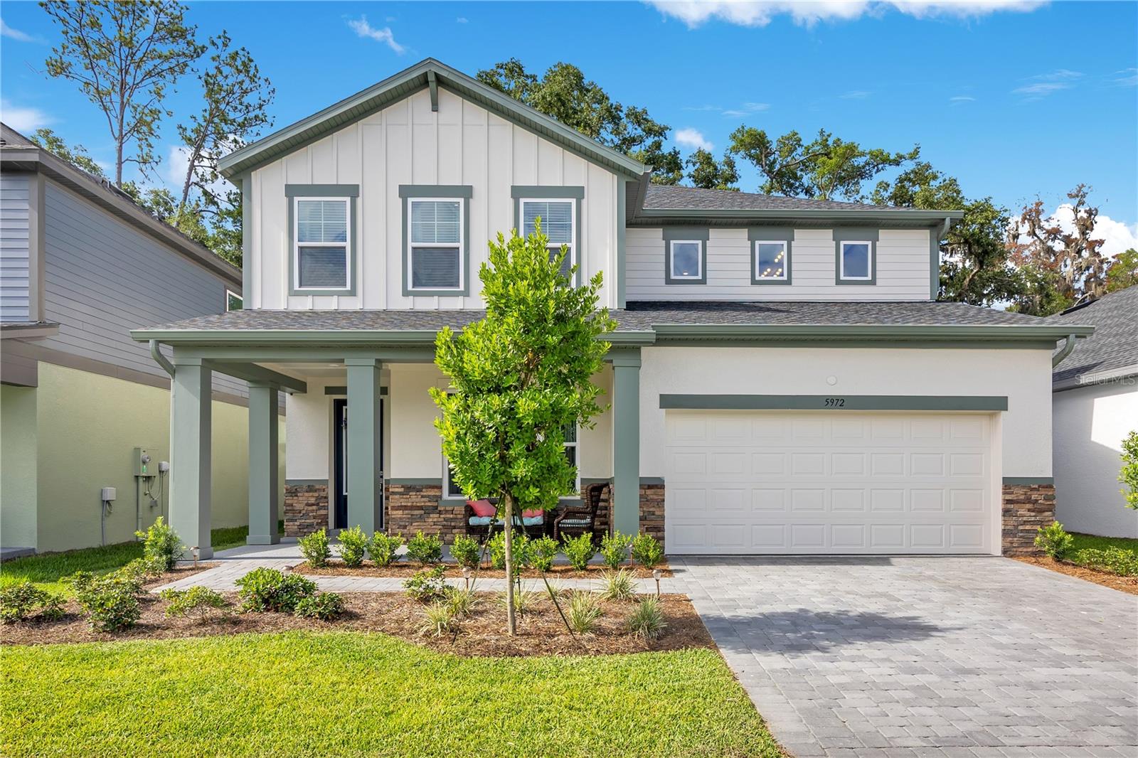 Why wait on new construction when like-new is ready right now? Skip the build timeline, skip the punch list, and skip the upgrade bill, because this one is already done. It even has a fence. Out front, a covered porch waits for rocking chairs and slow mornings. Step inside to a private study behind French doors, ready for that work-from-home space you've been promising yourself. Luxury vinyl plank runs across the entire first floor, including the stairs, no carpet, easy maintenance.  The kitchen is the center of it all. Bright white upgraded cabinetry. Upgraded quartz counters. A cooktop with a designer vent hood, a built-in wall oven, and a microwave. Pendant lights hang over a wide island where everyone gathers. It opens to the family room, then sliders open to an extended covered lanai. This premium lot backs to the woods, so the view stays private.  A first-floor guest bedroom with its own walk-in shower gives visitors their space. Upstairs, the primary bedroom sits under a tray ceiling and features a massive walk-in closet, and private ensuite that has been updated by the owners with new tile and a new frameless glass door, and upgraded quartz. The remaining bedrooms give the rest of the household room to spread out. A loft and a separate bonus room handle movie nights and game days. Even the laundry room is upstairs, where the clothes already are. The owners added what new buyers usually wait on. A fenced backyard. A whole-home water softener. Move in and skip the to-do list. The neighborhood gives you a resort-style pool, a playground, and shaded gathering spots by the water. Publix and local dining sit a short walk away. Grantham Point boat ramp and lighthouse, plus Downtown Historic Mount Dora at Donnelly Park, are a quick six minute drive. The 453 Connector is five minutes out, sending you south toward Winter Garden on 429 or north toward Sanford on the Wekiva Parkway. Like new. Already upgraded. Ready when you are.
