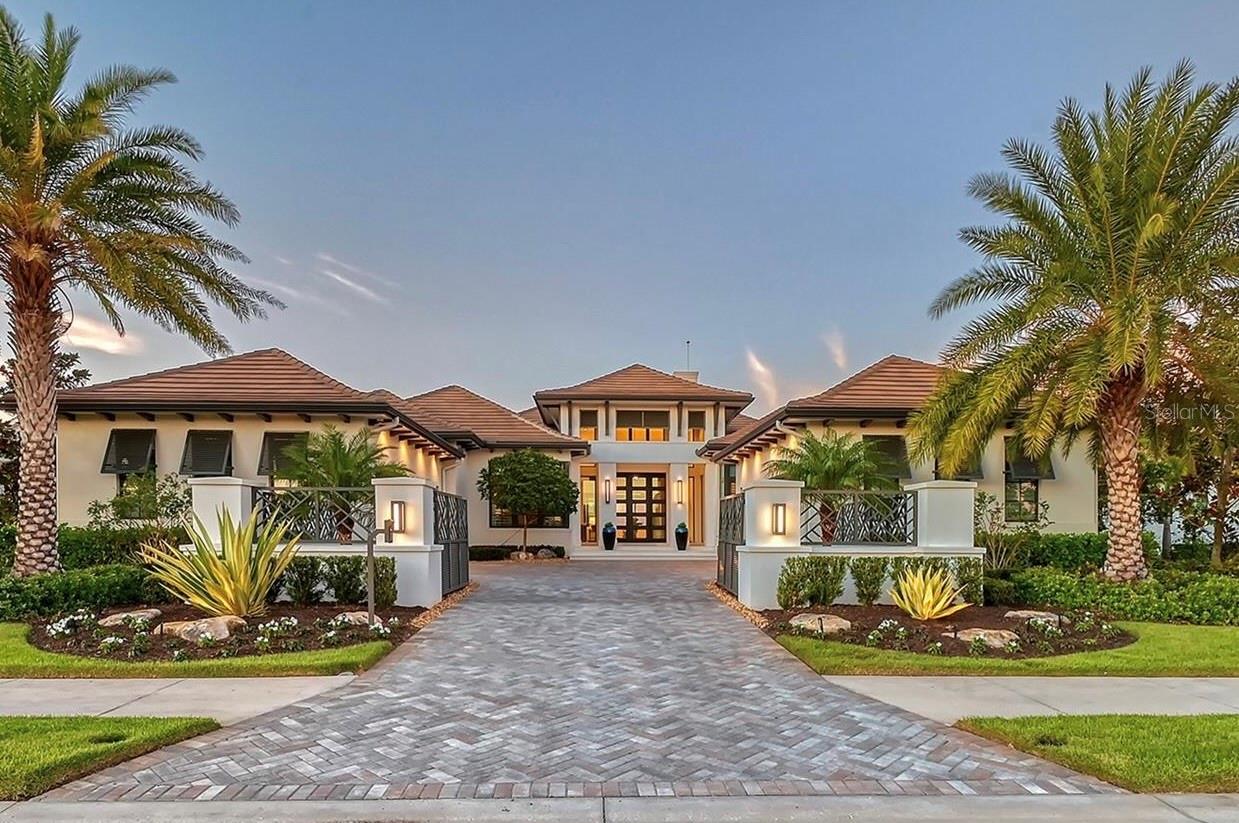 Professionally-designed and fully-furnished, this custom residence is situated on a premium lakefront homesite in The Lake Club and showcases breathtaking long-lake views and an unparalleled outdoor living experience. Thoughtfully designed for both luxury and comfort, the outdoor spaces include multiple fire and fountain features, a resort-style pool with a swim-up bar, a well-appointed cabana, and a state-of-the-art outdoor kitchen—creating an extraordinary setting, particularly at sunset. A wall of sliders in the great room and two sets of disappearing corner sliders—one in the dining area and another in the bonus room with an impressive wet bar—seamlessly blend indoor and outdoor spaces. Inside, floor-to-ceiling high-end finishes are evident throughout, complementing the professional-grade kitchen equipped with Wolf and Sub-Zero appliances and a thoughtfully designed hidden pantry. The primary suite is a spa-like retreat, featuring a private outdoor courtyard with a serene outdoor shower, while all guest suites offer en-suite baths with exquisite custom tile work. Architectural details, including custom ceiling and wall treatments, elevate the home’s refined aesthetic. Designed for both beauty and resilience, the home is constructed with hurricane-impact glass, whole-house surge and lightning protection, a whole-house generator, and advanced security and smart home technology. Additional highlights include an entry courtyard complete with motorized privacy gate, A/C in garages, a guest bath with a steam shower, a breakfast bar in the primary suite, a privately positioned office ideal for working from home, and so much more… Every element of this sophisticated residence has been curated for the discerning buyer, offering an exceptional lifestyle within The Lake Club’s prestigious setting where residents are treated to a wealth of amenities including a grand clubhouse, resort-style pools, fitness center, tennis courts, walking trails, and a calendar full of social activities, creating a lifestyle that is as luxurious as it is vibrant. Lakewood Ranch is the best-selling multi-generational community in the USA near world-class dining, shopping, beaches, and A+ schools.
