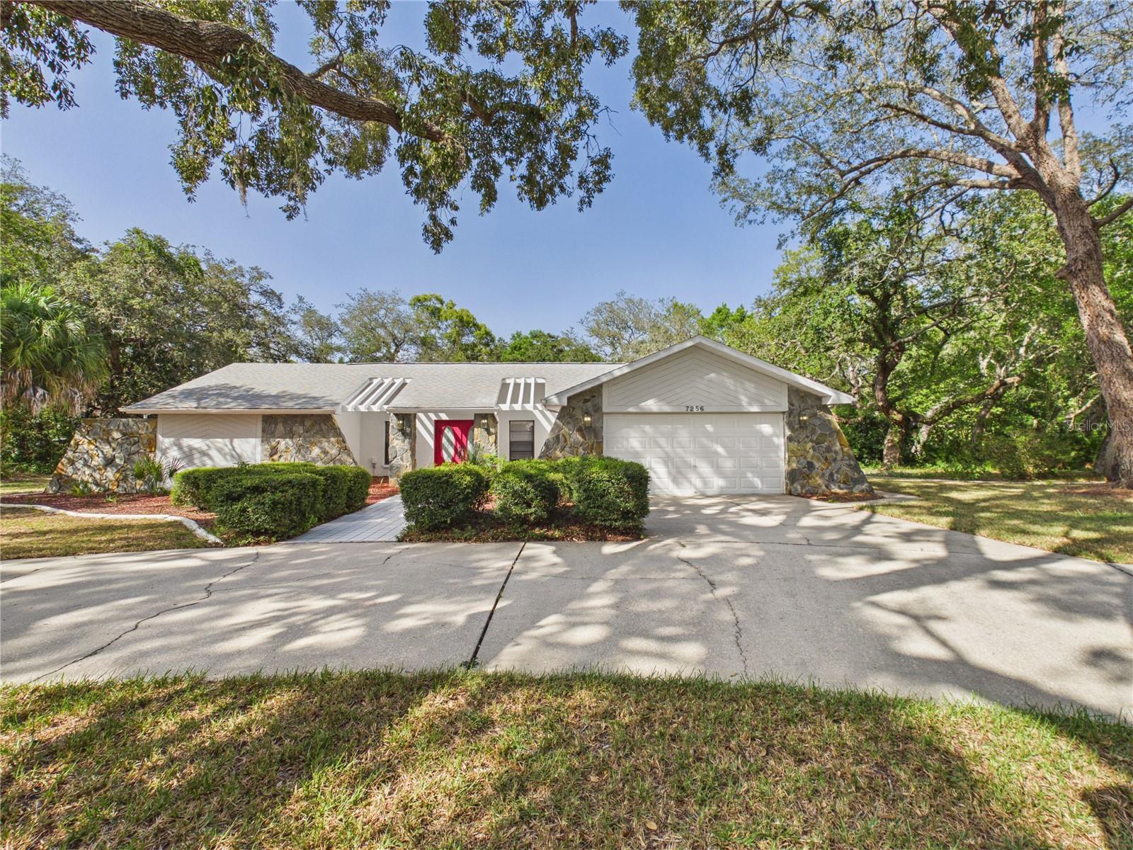 Welcome to 7256 Royal Oak Dr. This 3/2/2 offers the perfect blend of comfort, style and Florida living. Designed with a popular split floor plan, the home features two living rooms, a fireplace, multiple sliding glass doors that create a seamless connection between the interior and the outdoor living space. The updated kitchen and bathrooms provide modern finishes, with LVP flooring throughout, fresh interior and exterior paint and a new water heater offer peace of mind and move in ready convenience. Venture outside to your own backyard oasis featuring a sparkling pool and spa, an expansive screened lanai and a summer kitchen, perfect for entertaining year round. Towering oak trees and mature landscaping provide a beautiful natural backdrop, while the circular driveway enhances curb appeal and offers ample parking. Lake in the Woods offer 24 manned gated entrance, lakefront pavilion, tennis and pickleball, playground, dog park and boat and RV storage. The area is golf cart friendly.