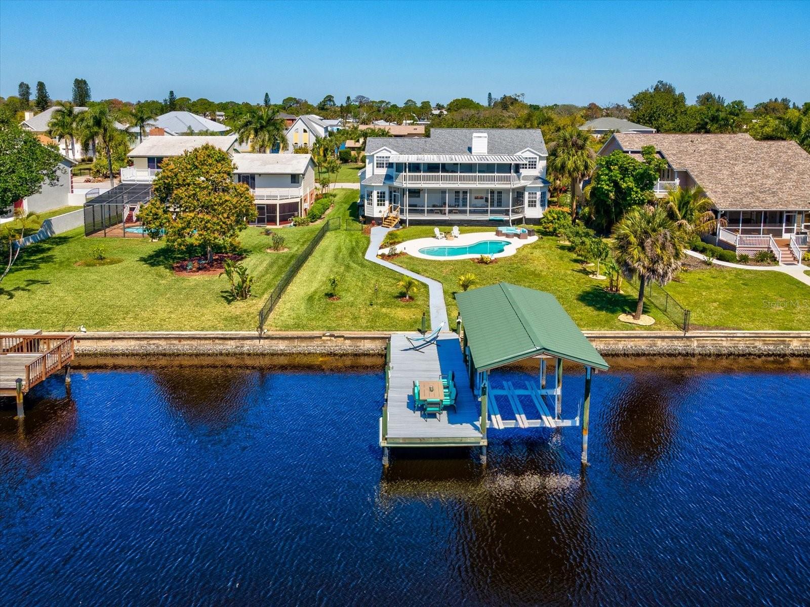 Waterfront Luxury with Panoramic Views! Experience elevated coastal living in this stunning 4 bedroom, 3.5 bathroom waterfront estate offering over 3,150 square feet of beautifully updated living space. Perfectly positioned along the Ruskin Inlet, this exceptional two-story Colonial-style residence captures breathtaking water views from nearly every room—with unforgettable sunsets as your daily backdrop. Step inside to a bright, open-concept floor plan designed for both effortless entertaining and everyday luxury. The home has been completely renovated with high-end finishes, including luxury vinyl plank flooring throughout, designer lighting, updated plumbing and electrical systems, and a reimagined layout that maximizes both space and function. At the heart of the home is the gourmet kitchen, featuring double-thick granite countertops, a premium stainless steel appliance package, Samsung induction double oven, and a brand-new picture window framing serene waterfront views. The kitchen flows seamlessly into expansive living and dining areas, enhanced by a beautifully redone fireplace. TWO primary suites, both private retreats, boasting panoramic water views! One of the suites offers a spa-inspired bathroom with marble finishes, and a full steam room—creating the ultimate sanctuary. A previously converted bedroom now serves as an oversized custom walk-in closet, while additional flex space offers the perfect option for a home office or bonus room. Step outside to your private backyard oasis, where indoor-outdoor living truly shines. Enjoy a resurfaced pool with expanded decking, screened lanais on both levels overlooking the water, lush tropical landscaping with fruit trees including tangelo, mango, sapodilla (nesbury/St. Julian), and bananas and daily dolphin and manatee sightings. For boating enthusiasts, this property is a dream come true with a covered dock and 13,000 lb boat lift providing deep water access—perfect for exploring Tampa Bay and beyond. Additional highlights include newer roof (approx. 2–3 years old) with 50-year warranty, newer AC systems (approx. 1.5–2 years) tankless water heater, tiled laundry room with utility sink and expanded outdoor walkway and living space. Ideally located near parks, dining, beaches, and major airports, this home offers the perfect blend of luxury, convenience, and true Florida waterfront living.