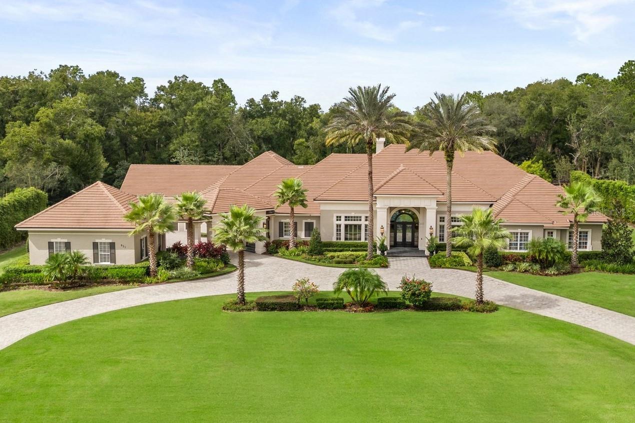 Welcome to an extraordinary estate blending timeless elegance with modern sophistication. Built by renowned luxury home builder Dave Brewer, this recently fully remodeled, executive residence showcases exceptional craftsmanship & offers an elevated living experience. Nestled within the prestigious 24-hour guard-gated Sweetwater Club, the property spans nearly three acres of meticulously landscaped grounds, creating a serene private retreat. A sweeping driveway welcomes you, framed by new custom landscaping. Lush grounds feature vibrant plantings, dramatic lighting, & thoughtfully designed outdoor living areas, setting the tone for a world-class lifestyle. Through grand arched double doors, the interior reveals a stunning open floor plan filled with natural light. Soaring ceilings & expansive windows highlight the home’s architectural beauty. Travertine flooring with intricate inlays flows throughout the main living spaces, while rich hardwood floors add warmth & elegance to the bedrooms. The gourmet kitchen is designed for a culinary enthusiast & outfitted with top-tier appliances, including dual ovens, a built-in refrigerator & freezer, and a second oven in the hidden butler’s pantry. Double-stacked granite countertops and a custom stone range hood elevate the space, while the expansive butler's pantry provides ample storage & prep areas for effortless entertaining. Each bathroom serves as a personal sanctuary. Luxurious finishes, double-stacked granite countertops, custom vanities, & full-wall stone-tiled showers with artistic inlays create spa-like experiences. The owner’s bath features a soaking tub & shower with multiple jets & a rain shower designed for relaxation. While another bathroom includes a steam room, sauna, & rain shower, offering a true wellness experience at home. Ideal for entertaining, the outdoor living space features a newly remodeled saltwater pool & hot tub finished with Italian tile & exposed aggregate, both equipped with advanced automated controls for effortless operation. A custom stone fireplace adds warmth & ambiance. The outdoor kitchen is fully equipped with stainless steel cabinetry, a new grill, side burner, sink, refrigerator, freezer, & television—perfect for hosting gatherings. Built-in Bose speakers throughout create the perfect atmosphere. Every element reflects expert craftsmanship, from detailed moldings & tray ceilings to beautifully textured walls. Laundry rooms combine style & function, including a steam unit & additional appliances to support outdoor entertaining. Modern amenities include three new gas water heaters, energy-efficient LED recessed lighting, & a high-end security system with 14 surveillance cameras. Exterior lighting by Fine Art Handcrafted Lighting highlights the home’s beauty day & night. The home offers exceptional flexibility with two private offices, a fitness room, a cozy media room, & spacious storage above the garage. These spaces can adapt to your needs as additional bedrooms, game rooms, or a home theater. Sweetwater Club offers private tennis & pickleball courts, a basketball court, & access to Sweetwater Beach on Lake Brantley. Enjoy boating, water skiing, fishing, sailing, & kayaking. This is a rare opportunity to own a property embodying luxury, privacy, & comfort at the highest level.