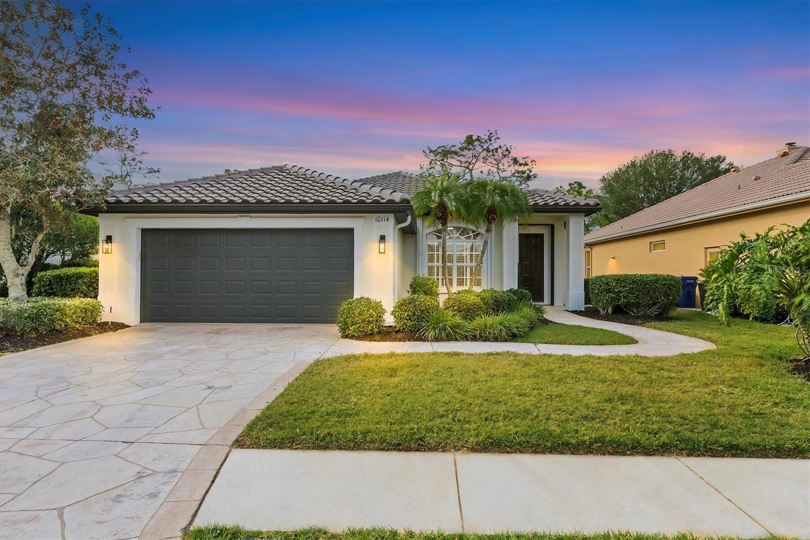 Introducing 10114 Glenmore Ave – A Newly Remodeled Golf Course Retreat in River Club! New tile roof in 2024 and stunning, high-end renovations throughout make this residence a rare and luxurious offering in the coveted golf and country club community of River Club. This beautifully reimagined 3-bedroom home, complete with a dedicated study and a two-car garage, offers nearly 2,000 sq. ft. of refined elegance and effortless living. From the moment you arrive, meticulous updates and thoughtful craftsmanship define every room. A brand-new, bright and stylish kitchen serves as the centerpiece of the home, featuring soft-close shaker cabinetry, gleaming quartz countertops, a designer backsplash, and sophisticated new lighting. The deep stainless sink and suite of new stainless-steel appliances—including built-in wall oven, microwave, and electric cooktop with exhaust hood—make this kitchen as functional as it is beautiful. Perfectly placed just off the kitchen, the dining area enjoys serene views of the manicured golf course and is anchored by a modern, statement-making chandelier. After dinner, retreat to the living area where a sleek feature wall frames a built-in flatscreen television and a contemporary horizontal electric fireplace—creating a luxurious yet inviting space for evening relaxation and entertaining. Wide-plank engineered hardwood flooring flows throughout the home, unifying the spaces with warmth and sophistication. Both bathrooms have been completely transformed with new soft-close cabinetry, designer faucets, porcelain tile, upgraded sinks, and new fixtures throughout. For peace of mind and efficiency, major systems have been updated as well, including a new hot water heater and a 2020 A/C system. Hurricane shutters further enhance comfort and security. Step outside to your private Florida oasis. The resurfaced pool (completed in 2019) sparkles in the sun, surrounded by an updated lanai offering new flooring, new screens, and a covered seating area—ideal for outdoor dining, lounging, or enjoying the tranquil golf course backdrop. Even the garage has been elevated with new front-load washer and dryer and epoxy flooring for a pristine finish. This home is move-in ready, and furnishings may be purchased separately for a seamless transition. Located in a maintenance-free section of River Club, residents enjoy the luxury of low-maintenance living with access to community amenities including golf, a heated pool, a beautifully appointed clubhouse, and tennis facilities. All of this is just minutes from the shopping, dining, and entertainment of Lakewood Ranch, as well as top-rated schools, making this property perfectly suited for the buyer who desires convenience, elegance, and a premier lifestyle. A rare opportunity to own a beautifully renovated home in one of the area’s most desirable communities—schedule your private showing today before this one is gone.