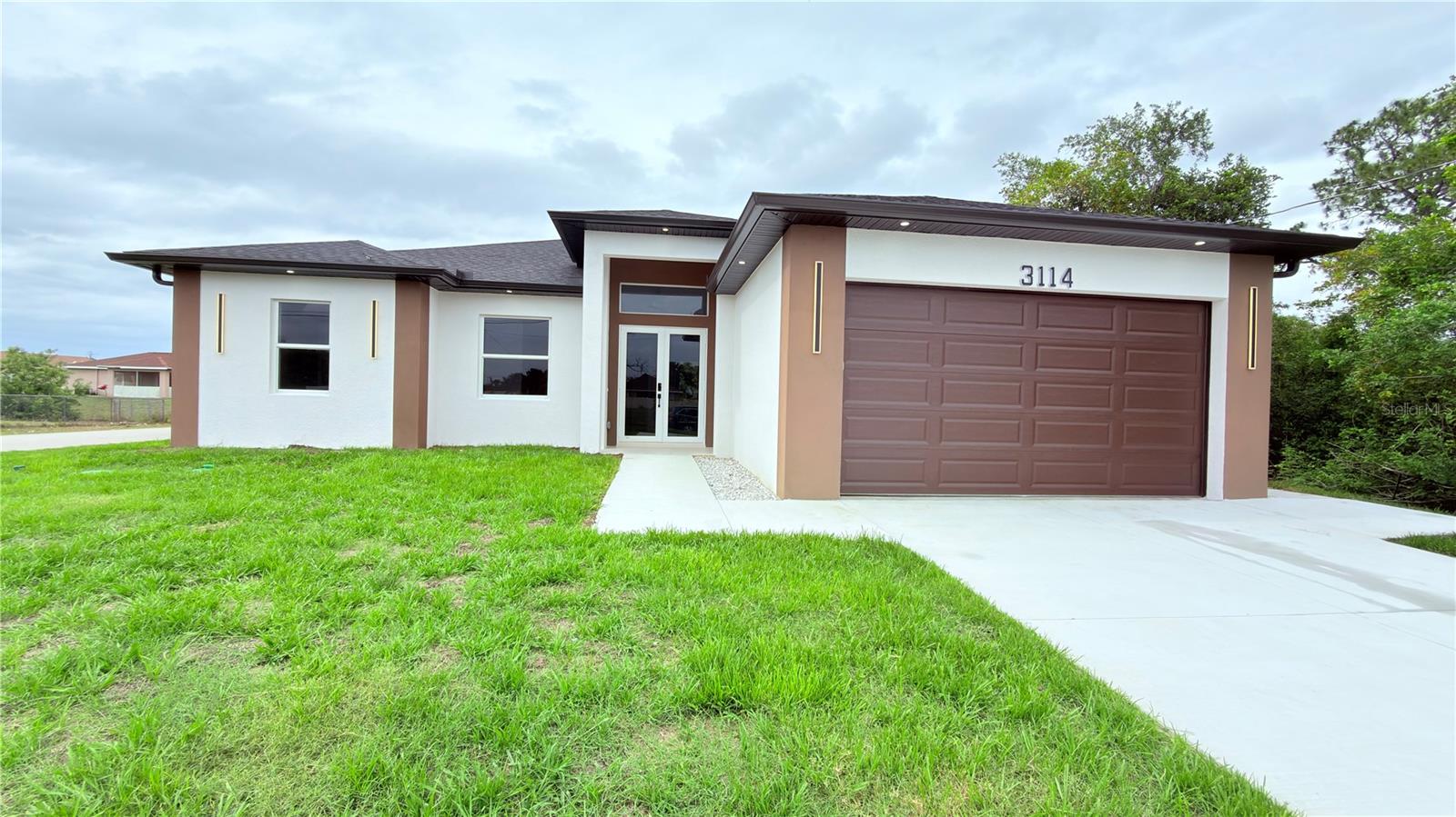 New Construction Home with an Apartment! Welcome to this beautifully crafted new construction home offering nearly 2,000 sq. ft. of living space, designed with comfort, style, and flexibility in mind. This exceptional property features 4 bedrooms, 3 bathrooms, and a spacious 2-car garage, including a private apartment with its own separate entrance. The apartment includes 1 bedroom, living area, kitchen, bathroom, and washer/dryer hookups already in place — ideal for extended family, guests, or potential rental income opportunities. Situated on a desirable corner lot on a dead-end road, just off Lee Blvd, this home offers the perfect combination of convenience, privacy, and functionality. Inside, you’ll find elegant porcelain tile flooring throughout, impact windows and doors, and a bright open-concept layout filled with natural light. The modern kitchen is designed to impress, featuring quartz countertops, wood cabinetry, and stainless steel appliances — perfect for everyday living and entertaining. The owner’s suite offers a relaxing retreat with dual walk-in closets and a beautiful primary bathroom with double sinks. Step outside and enjoy true Florida living on the spacious lanai, complete with a summer kitchen — perfect for outdoor dining, family gatherings, and year-round entertaining. This home offers the ideal blend of modern design, flexible living space, and a prime location.