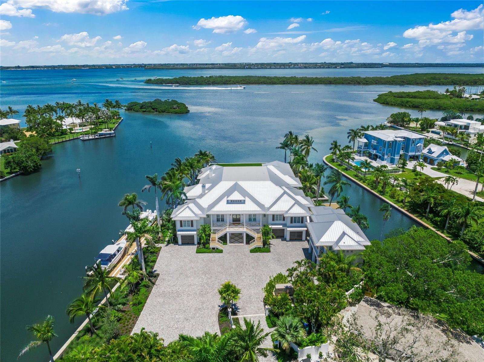 Welcome to your private, gated estate on Longboat Key, where coastal luxury meets effortless sophistication. Boasting over 730 feet of water frontage, this stunning property offers panoramic views of Whitney Bayou and Harris Canal and provides the ultimate waterfront lifestyle. 
With 9,243 square feet of air-conditioned living space and a total of 21,562 square feet on over an acre of pristine land, this estate is a masterpiece of design and craftsmanship. Designed in the timeless British West Indies style, this home showcases vaulted ceilings, extensive trim detailing, white oak floors throughout, and two fireplaces, creating an ambiance of elegance and warmth.
The expansive covered patios and porches invite you to embrace the serenity of waterfront living, while the heated pool and an impressive 13' x 13' hot tub serve as the ultimate retreats. A custom outdoor fire pit, two outdoor kitchens, and indoor and outdoor pool tables elevate the entertainment experience.
For boating enthusiasts, this estate is unrivaled, featuring four low-profile boat lifts—the largest accommodating vessels up to 30,000 pounds, the second suitable for a vessel up to 20,000 pounds, and the third and fourth lifts each with a 5,000-pound capacity, ideal for jet skis, kayaks, and paddle boards. Located just 10 minutes from the Gulf of Mexico by boat and 5 minutes to Shore and Mar Vista restaurants, this is the perfect haven for life on the water.
Inside, the Wolf Sub-Zero appliances provide top-tier performance in a gourmet kitchen built for culinary excellence. A Control4 smart home system offers seamless automation throughout, while HVAC-equipped garages ensure comfort year-round. The multiple garages can accommodate up to 9 cars, and the massive driveway can host 20+ vehicles.
The residence boasts six spacious bedrooms, each with an en-suite bathroom, plus an additional full bath and two half baths. Designed for both productivity and leisure, the home features his and hers offices, a media/theater room, a fully equipped gym, sauna, golf simulator, tackle garage, and a workshop.
A private guest suite with a separate entrance includes a kitchenette, dining room, living room, bedroom, and bathroom, offering a luxurious retreat for visitors. With two state-of-the-art elevators, expansive landscaping, and a maintenance-free turf yard, this estate blends modern convenience with natural beauty.
Ideally located near pristine beaches, world-class shopping, and gourmet dining, this estate is the epitome of waterfront elegance and exclusivity. Experience the pinnacle of coastal living—this is truly paradise found.