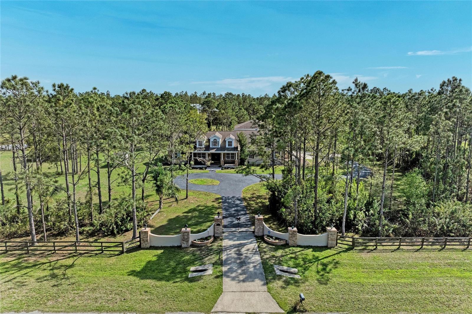 One or more photo(s) has been virtually staged. PRIVATE 10-ACRE ESTATE IN PANTHER RIDGE *$650,000 below appraised value. 

This exceptional estate offers the ultimate in privacy and security, featuring its own private gate and a fully fenced 10-acre property. As you enter, a picturesque circular driveway and charming country-style front porch create a warm and inviting first impression.

Step through the double glass doors into a bright and elegant living room, where large French doors frame stunning views of the salt water pool and outdoor living space. The formal dining room is beautifully accented with architectural arches, adding timeless character. A front-facing bedroom provides the perfect opportunity for a private office or guest suite.

The heart of the home is the spacious kitchen, designed for both functionality and entertaining. It opens seamlessly to the family room and features double wall ovens, a large custom pantry, a central island, and an expansive eat-in area surrounded by oversized windows. The family room boasts soaring ceilings and a gorgeous wood-burning fireplace, with French doors leading directly to the pool area for effortless indoor-outdoor living.

The primary suite is a peaceful retreat, complete with French doors, dual closets, and a spacious en-suite bathroom featuring a Jacuzzi tub, walk-in shower, and dual vanities. This home also offers a rare second primary suite on the main level, with its own private bathroom including a Jacuzzi tub and walk-in shower—ideal for multi-generational living or extended guests.

Additional living space includes multiple guest bedrooms, two upstairs bedrooms with a shared bathroom, and a large bonus room. A unique feature under the staircase includes a custom-built space designed to accommodate a 30-gallon aquarium.

Built with safety and resilience in mind, the home includes a reinforced concrete hurricane shelter with solid poured walls, a reinforced ceiling, and exterior locking doors. Additional features include hurricane-impact window film, a full security system with internet protocol cameras, and a commercial-grade Generac liquid-cooled QuietSource 25kW standby generator, supported by a 1,000-gallon propane tank—capable of powering the home for weeks. 2nd floor is block construction. New AC, new oven, roof 2019, addition to home 2012.

The property also features a fenced dog run and is perfectly suited for animal lovers.

The 10-acre grounds are truly breathtaking, complete with a stocked pond for fishing and a large barn 30x 40. Located in the sought-after Panther Ridge community, residents enjoy access to scenic horse and walking trails. This equestrian-friendly neighborhood welcomes horses and chickens (no roosters), cows, offering a true country lifestyle while remaining just minutes from shopping, dining, and everyday conveniences.