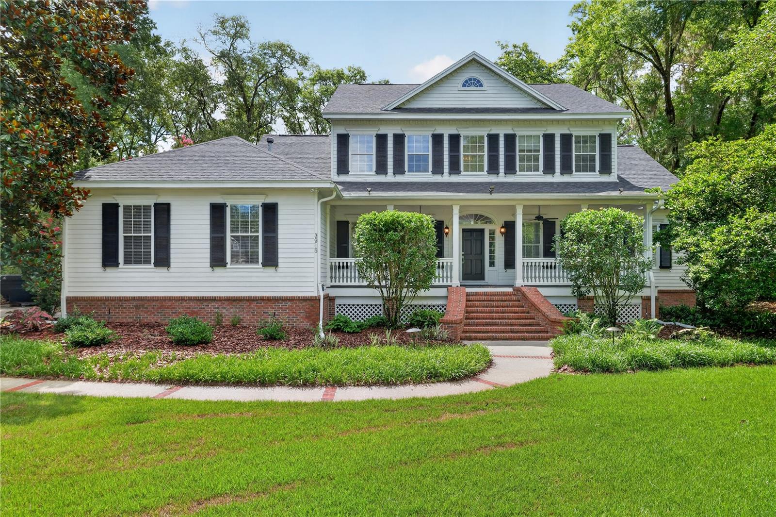 Virtually Staged. Nestled beneath a canopy of mature oaks in the sought-after Haile Plantation area, this timeless Southern Living-style estate blends classic architecture with elegant everyday living. Situated on an expansive 2/3-acre beautifully landscaped homesite in Albury Round, this custom residence offers exceptional curb appeal with its large front porch, stately columns, and welcoming brick staircase entry.
Spanning 3,294 heated and cooled square feet, the thoughtfully designed floor plan features 4 bedrooms, 4 baths, great room, formal dining, a private study, and a versatile bonus room. Enter through the expansive foyer, flanked by a formal banquet-sized dining room adorned with a tray ceiling, wainscoting, and crown molding, and a handsome study featuring extensive custom built-ins, crown molding, and ample space for both work and relaxation.  The heart of the home is the dramatic great room, highlighted by soaring two-story ceilings, gleaming wood floors, an electric fireplace framed by custom millwork and mantel, and an impressive Restoration Hardware chandelier. French doors open to the newly refurbished deck, creating seamless indoor-outdoor living. The kitchen features white cabinetry, a large center island with a 5-burner gas cooktop, double ovens, microwave, newer refrigerator and dishwasher, and opens to a spacious breakfast area with picturesque views of the park-like backyard and deck access. The downstairs primary suite is a private retreat, filled with natural light from numerous plantation-shuttered windows and featuring french doors to the deck. The oversized custom walk-in closet offers abundant built-in storage and drawer space. The primary bath includes dual vanities, a jetted tub, large walk-in shower, and private water closet. A full guest bath conveniently serves the main level.  Upstairs, three generously sized bedrooms each offer walk-in closets. One bedroom enjoys a private en-suite bath and convenient laundry chute, while two additional bedrooms share a spacious adjoining bath. Completing the upper level is a bonus/media room featuring wood floors, an electric fireplace, floor-to-ceiling shelving, multiple storage closets, and a large screen television, creating the perfect space for movie nights, gaming, or relaxing with family and friends.
Designed for entertaining and enjoying Florida’s natural beauty, the expansive deck overlooks the lush, park-like grounds and connects to a charming courtyard area and winding walkway leading to a large brick entertaining terrace at the rear of the property. Additional features include an inside laundry room and an oversized two-and-a-half-car garage with a dedicated golf cart bay.  Recent updates provide peace of mind and include a new 2025 roof, two 2018 HVAC systems, and a newer tankless water heater. Ideally positioned near Hawkstone Country Club with premier golf, as well as two Haile Villages with dining and boutique shopping. Located near top-rated schools, the University of Florida, and UF Health, this is a rare opportunity to own a signature residence that embodies the very best of classic southern living in Gainesville.