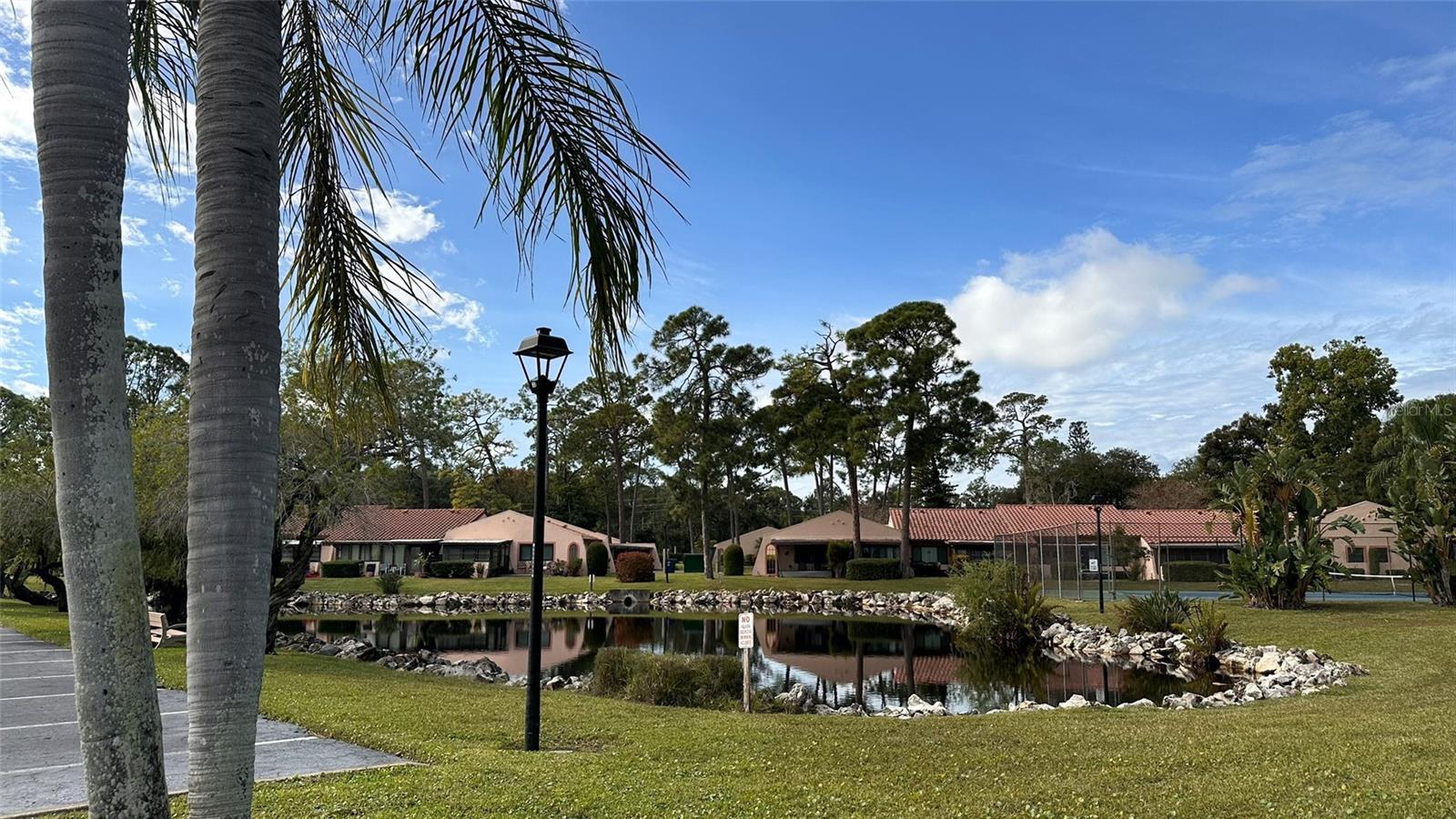 Ideally located in central Seminole, this community offers a peaceful, green sanctuary with stunning, mature oaks, swaying palms, and scenic pond water views by the clubhouse and second village—all just walking distance to Lake Seminole Park and minutes from pristine Suncoast beaches and thriving downtown St. Pete.

This rare end-unit corner garden villa lives large, featuring the largest 1-bed/1-bath layout in the community (760 sq ft heated).

Fresh Updates: Bright and airy with cathedral ceilings in the great room, tile and laminate flooring throughout, and a brand-new, stylishly updated bathroom.

Bonus Space: Step into the massive 200+ sq ft enclosed Florida room/lanai—double the size of standard units—featuring wall-to-wall windows and a private door to the lush backyard.

Convenience & Peace of Mind: Covered 3-sided carport is attached directly next to your front door, plus a private storage closet on the front patio. Big-ticket mechanicals are already taken care of (Water Heater ~2 yrs, HVAC ~4.5 yrs).

Enjoy Spanish-style architecture, underground utilities, and resort-style amenities including a spacious clubhouse, sparkling pool, tennis, and pickleball. Quiet, natural, and connected—schedule your private tour today!