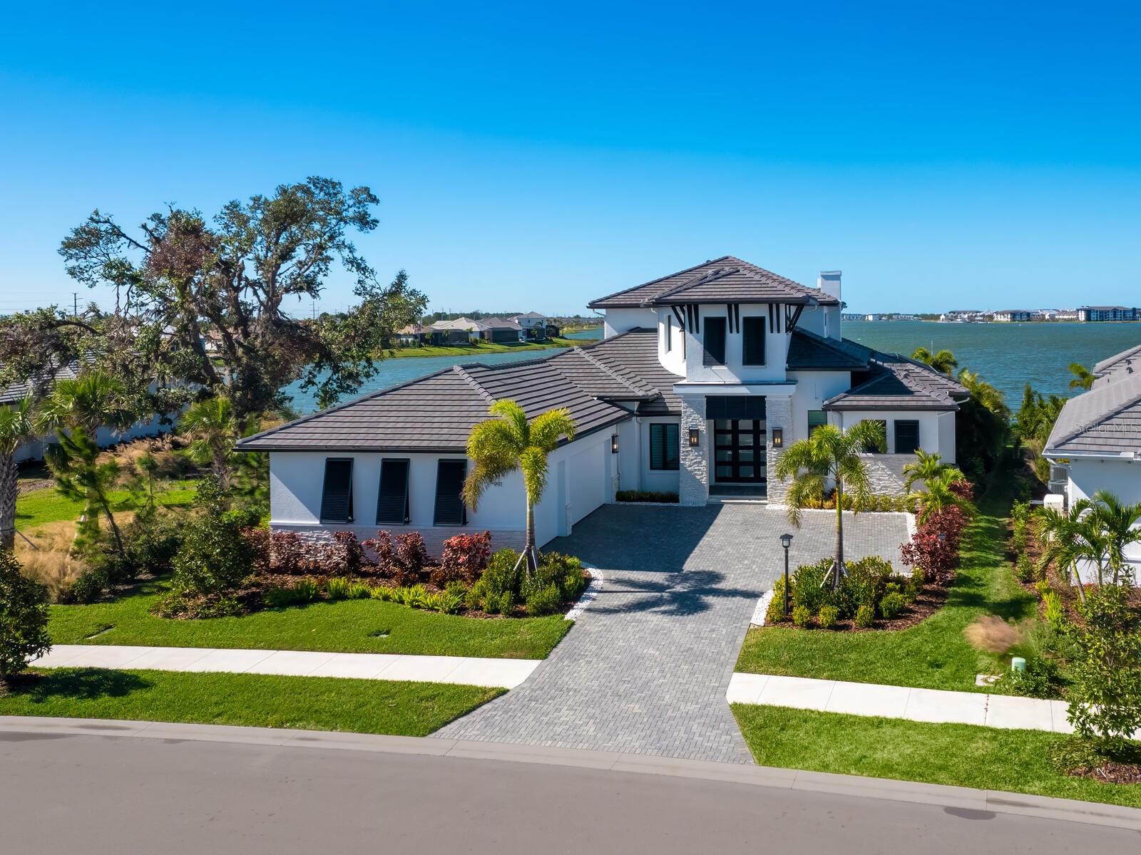 Nestled within the desirable Waterside enclave of Lakehouse Cove in Sarasota, 991 Seascape Place is a masterpiece of refined coastal luxury. This one-of-a-kind estate spans over 7,000 total square feet of exceptional design, offering an unmatched lifestyle on the finest waterfront lot in the community. The exterior is a private oasis, featuring lush, meticulously curated landscaping, a resort-inspired pool with an advanced mosquito misting system, integrated Sonos speakers, a cutting-edge outdoor kitchen and fireplace, and panoramic screens that frame Sarasota’s most spectacular sunsets. Step inside to discover a world of sophistication. Expansive glass walls, soaring ceilings, and exquisite designer finishes create a bright and airy ambiance that celebrates the art of luxury living. The open-concept layout seamlessly merges indoor and outdoor spaces, offering uninterrupted views of tranquil waters from nearly every room. At the heart of this home lies a gourmet kitchen, a culinary dream outfitted with top-tier Thermador appliances, sleek quartz countertops, two dishwashers, and a discreet butler’s pantry. Each of the four en-suite bedrooms is a retreat unto itself, with the primary suite serving as the ultimate sanctuary, boasting a spa-inspired bath with heated floors and a raised soaking tub designed for pure relaxation. Indulge in a wealth of additional amenities that elevate the home to an unparalleled level of luxury. A state-of-the-art media room sets the stage for cinematic experiences, while a private home gym with an infrared sauna and a dedicated wellness room cater to your health and relaxation needs. For wine enthusiasts, a climate-controlled wine cellar with capacity for over 400 bottles ensures your finest vintages are impeccably stored. The oversized garage provides ample space for vehicles and storage and offers two EV chargers, while smart-home technology seamlessly integrates convenience and sophistication into everyday living. This exquisite residence is mere steps from Lakehouse Cove’s premier amenities, including a waterfront pool, a stylish clubhouse, a fire pit lounge, a fitness center, and recreational courts for pickleball and tennis. Additional highlights include a pet park, playground, and access to a charming community ferry that offers rides to the nearby retail district of Waterside Place.  This chic cove located in "Downtown" Waterside offers a unique experience for shopping, dining, fitness, and events along the shores of Kingfisher Lake which is over a mile long.  Waterside Place has something for everyone.  Numerous restaurants, brewery, yoga studio, a salon, spa, clothing boutiques, coffee shop, jewelry store, pilates studio, kayak rental and launch.  It also plays host to the #1 Farmers Market in Florida. At 991 Seascape Place, luxury meets lifestyle, creating an unrivaled opportunity to embrace Sarasota's newest and most coveted living experience.