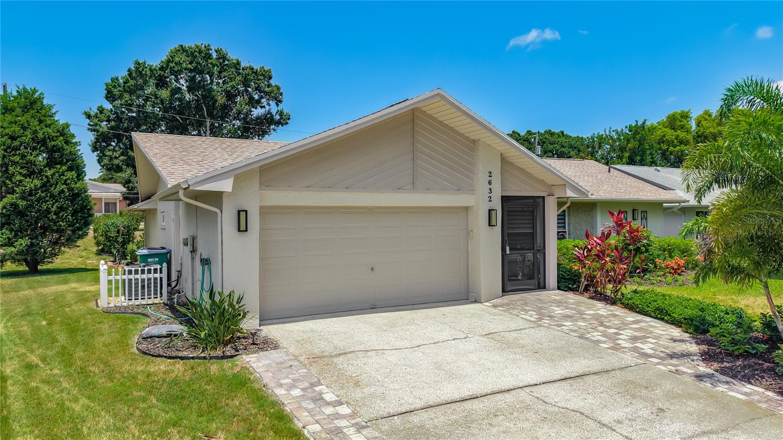 Welcome to this beautifully updated 2-bedroom, 2-bath residence, offering over 1,750 square feet of elegant living space in Palm Harbor’s premier 55+ golf community, Highland Lakes. Step inside to discover a thoughtfully designed floor plan featuring a fully renovated kitchen that effortlessly flows into the spacious main living area, perfect for entertaining or relaxing. Enjoy the convenience of an attached 2-car garage, an expansive temperature-controlled Florida Room, and an inviting outdoor living area with limitless possibilities. Sunlight pours through large, updated windows, illuminating every corner with warmth and natural light. The living room showcases a custom accent wall with built-in cabinetry and a striking stone-faced electric fireplace, creating a welcoming focal point. The adjacent dining area features a handcrafted built-in banquette - ideal for gatherings both large and small. The chef-inspired kitchen is a true showpiece, boasting granite countertops, sleek modern cabinetry, and stainless steel appliances, including a brand-new (2025) induction cooktop, refrigerator, and dishwasher. Recessed lighting, extensive built-in pantry storage, and a convenient breakfast bar adjoining the family room make this kitchen as functional as it is beautiful. Retreat to the serene primary suite, which offers a spa-like en suite bath, a spacious walk-in closet with custom organizers, and sliding doors leading to the Florida Room. The luxurious primary bath features a modern vanity with an integrated sink, a custom tiled walk-in shower with dual showerheads, and a seamless glass enclosure. The versatile second bedroom provides ample comfort for guests or hobbies, with its own large walk-in closet with custom organizers and a nearby guest bath. The guest bath exudes modern charm, complete with a floating vanity and vessel sink, a custom tiled walk-in shower surrounded by glass, and stylish wood-look tile flooring. The expansive Florida Room opens to a lush green space featuring a private pergola and an open patio with a retractable awning- perfect for enjoying the outdoors year-round. Relax among tropical landscaping and a thoughtfully designed succulent garden, embracing the quintessential Florida lifestyle. Recent major upgrades include a NEW roof (2023), NEW HVAC and ductwork (2025), fresh interior and exterior paint (2026), an epoxy-coated garage floor (2026), and professionally landscaped front and rear yards (2024). Located in a non-evacuation zone, this home offers peace of mind and year-round comfort. Highland Lakes residents enjoy an exceptional, resort-style lifestyle with a low HOA fee covering unlimited golf on three private executive courses, tennis, pickleball, bocce, shuffleboard, and an active clubhouse filled with social events and fitness classes. There’s also a lakeside lodge on Lake Tarpon, featuring a private boat ramp, fishing pier, and community pontoon boats. Additional highlights include free RV and boat storage, golf cart-friendly streets, and proximity to award-winning Gulf beaches, fine dining, shopping, medical centers, major airports, and a cruise port. This remarkable home blends sophistication, comfort, and active Florida living. Come take a look…You’ll love what you see!