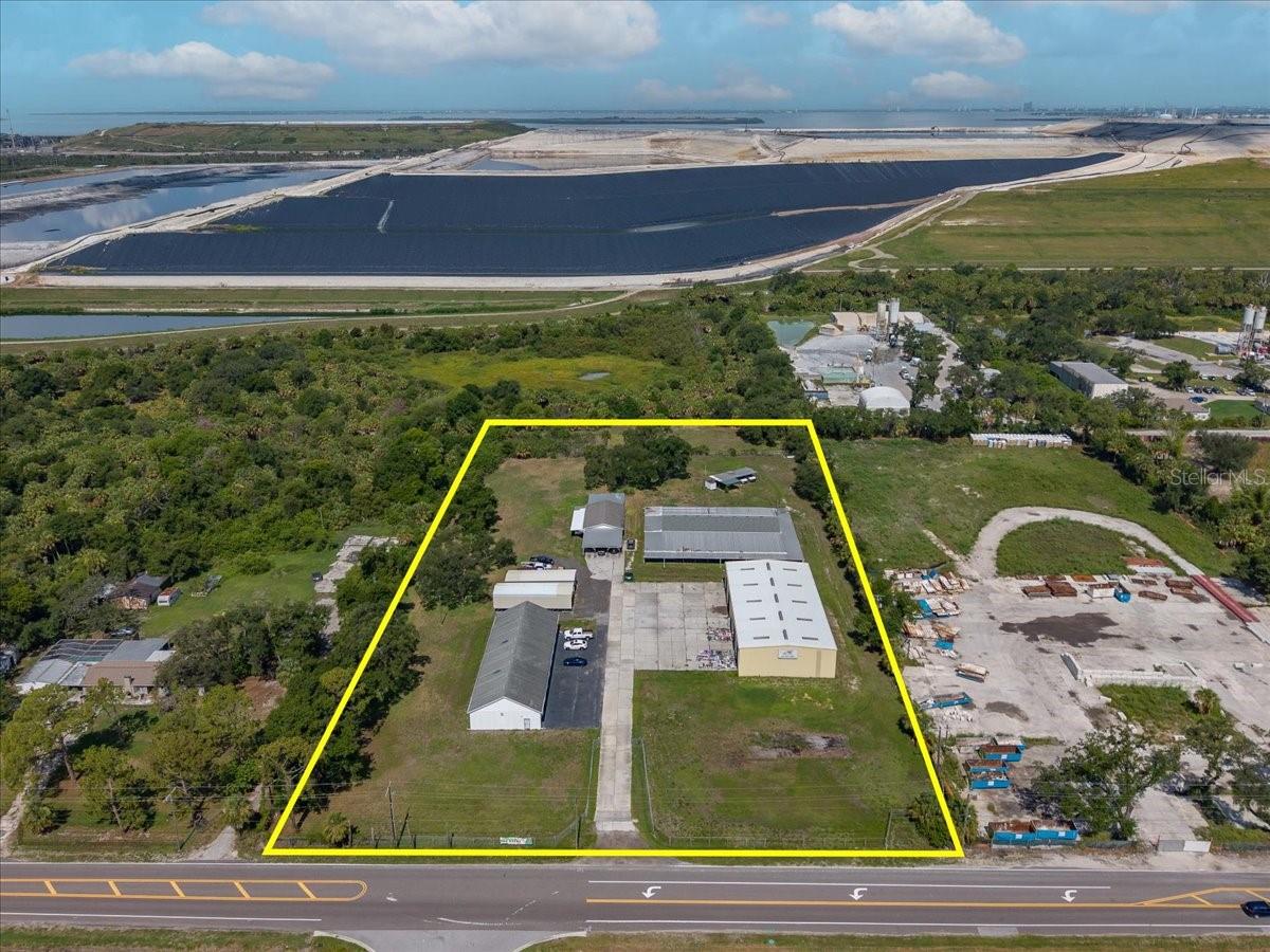 Rare opportunity to own more than 5 fully fenced commercial acres in the heart of Riverview, offering exceptional flexibility for contractors, service companies, industrial users, fleet operations, equipment storage, or investors. With four separate buildings totaling nearly 20,000 square feet, this property is well-equipped to support a wide variety of business operations. The approximately 2,950-square-foot office building (95.1' x 31') serves as the administrative hub of the property and features multiple offices, a kitchenette, restroom, and a covered wraparound porch providing shaded outdoor workspace and convenience for employees and visitors. The impressive 7,000+ square-foot prefabricated metal building (120.5' x 60.3'), constructed in 1994, offers three-phase electrical service and multiple overhead doors, making it ideal for warehouse, manufacturing, fabrication, or equipment storage. An eight-bay garage building measuring approximately 101' x 40' provides outstanding space for fleet vehicles, service equipment, or workshop use, while an additional storage building measuring approximately 48.5' x 30.3' includes a restroom and offers even more operational flexibility. Two of the buildings were constructed in 1969 with durable block construction and trussed shingle roofs, while the additional block storage building was completed in 2010. The property is serviced by private well and septic systems and provides abundant outdoor space for vehicle parking, material storage, equipment laydown, or future expansion. Conveniently located with easy access to US-301, I-75, the Selmon Expressway, and the greater Tampa Bay area, this unique commercial property combines acreage, multiple functional buildings, and outstanding versatility in one of Riverview's rapidly growing business corridors. Whether you're expanding an existing operation or seeking an investment with exceptional long-term potential, this property is ready to meet your business needs.
