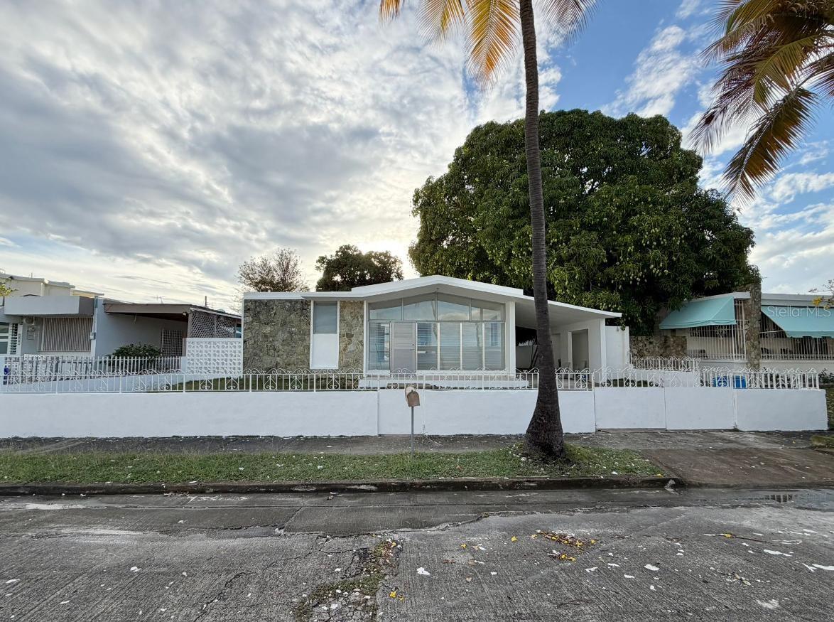 This solid concrete construction home offers 1,760 square feet of Gross Living Area. The layout includes 4 bedrooms, each with its own closet, 2 full bathrooms, living room, dining room, kitchen, laundry area, family room, and interior patio. The property also features 2 additional closets located in the exterior area at the entrance to the bedrooms, providing above-average storage space.
The lot measures 499.41 square meters. Includes a covered carport for one vehicle and 2 exterior storage closets measuring 21’ x 14’.

Property located in Urb. Valle Verde, an established sector of Ponce, with access to main roads and nearby services.