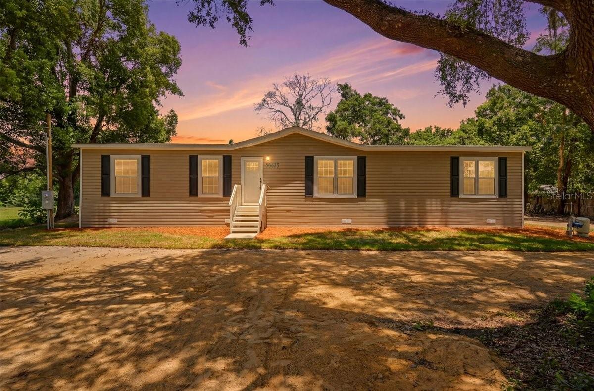 Brand new 2026 manufactured home situated on a 0.50-acre lot in Zephyrhills Florida. This 3-bedroom, 2-bathroom home features 1,580 sq ft of living space with an open-concept floor plan, 8-foot flat ceilings throughout, and upgraded vinyl flooring in the main living areas. The kitchen is equipped with a center island, 42-inch overhead cabinetry, stainless steel side-by-side refrigerator, smooth-top electric range, dishwasher, single-bowl stainless steel sink, and ceramic tile backsplash. Sliding glass doors in the dining area provide access to the exterior. The living room features decorative accent ceiling beams and a built-in entertainment center. The primary suite includes a walk-in closet and an en-suite bathroom fitted with dual square China sinks, 60-inch Duma shower with sliding glass doors, a freestanding soaking tub, and a decorative accent wall. The split-bedroom layout positions two additional bedrooms with walk-in closets opposite a full guest bathroom featuring a 60-inch tub/shower combination. Additional interior features include a dedicated utility room with a utility sink, storage cabinets, and folding station. the exterior features vinyl lap siding, OSB wrap, 3:12 roof pitch with dormer, and a Craftsman front door. Located in East Pasco County near US-301 and SR-54, this property offers convenient access to local amenities and regional travel corridors toward Wesley Chapel, Lakeland, and Tampa. Local area recreational options include Zephyr Park, Hercules Park, Crystal Springs Preserve, and Hillsborough River State Park for hiking, kayaking, and outdoor activities. Nearby points of interest include local golf courses (such as the Zephyrhills Municipal Golf Course and Links at Lake Bernadette), the Sarah Vande Berg Tennis Center, historic downtown Zephyrhills, the Depot Museum, and Skydive City.