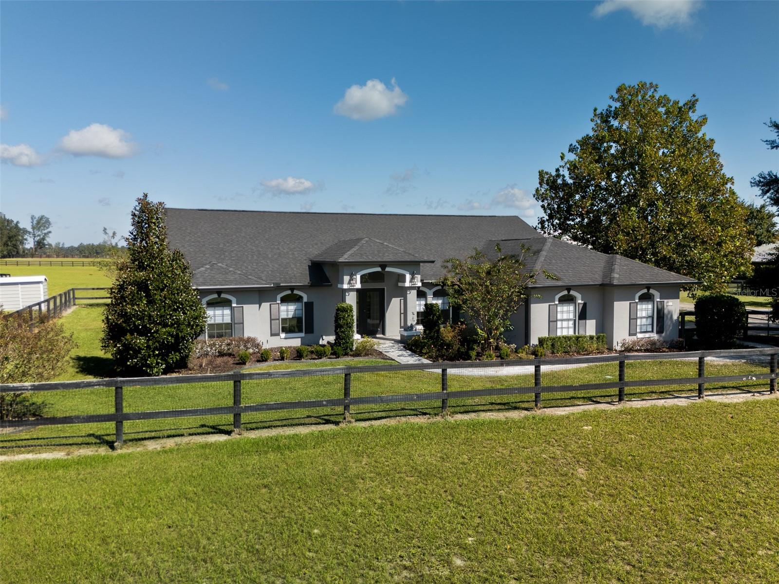 This fully fenced 10-acre farm offers the perfect blend of comfort, convenience, and equestrian functionality—all less than 15 minutes from the World Equestrian Center! Dotted with oak trees, this property is thoughtfully designed for both relaxed living and serious equestrian pursuits. The 4-bedroom, 2-bath home features an open, inviting layout filled with natural light. The kitchen boasts a large island and extensive wooden cabinetry, providing generous storage and a warm, welcoming space for cooking and entertaining. The primary suite includes tray ceilings, dual sinks with a vanity, a spacious walk-in shower, and a walk-in closet. Step out back to the screened-in patio, complete with an in-ground pool and plenty of space for relaxing or gathering with friends and family. Equestrian amenities include a 6-stall shed row barn with roll-up doors, an air-conditioned tack and feed room, and wash racks. The property also features an irrigated arena with all-weather GGT footing, a round pen, and 5 fenced paddocks, 4 of which are irrigated, providing ample space for riding and turnout. An additional metal equipment barn/RV port adds even more versatility, offering a kitchen area, full bathroom, and generous space for equipment, feed, and tack. With its prime location near world-class equestrian facilities, functional layout, and serene country setting, this property presents a rare opportunity to experience refined country living in the heart of Florida’s horse country.