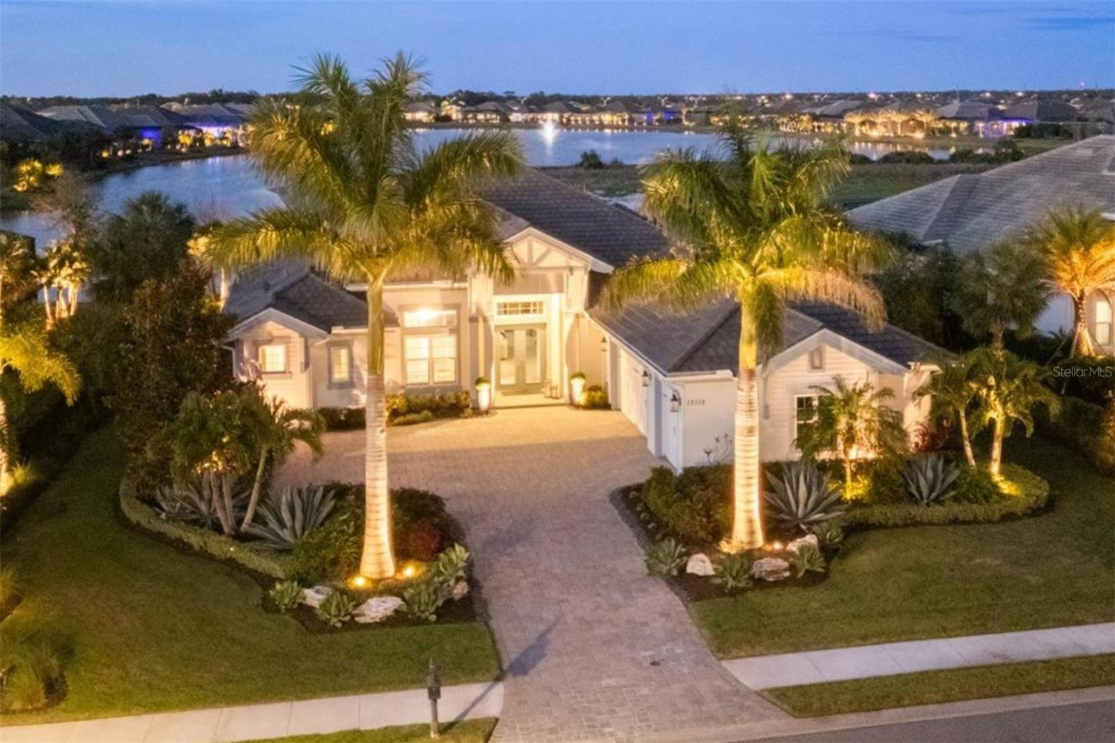 Under contract-accepting backup offers. Experience refined Florida living in this stunning Stock Merano model, a beautifully designed waterfront residence offering 3,600 square feet of luxurious living space. From the moment you step inside, you’re welcomed by a light and airy ambiance, enhanced by soaring ceilings, neutral porcelain tile flooring, elegant window treatments, and a soft, modern color palette throughout. Designed with both comfort and entertaining in mind, the expansive great room showcases impressive 14-foot coffered ceilings, custom owner-installed cabinetry with illuminated shelving, and a stylish dry bar complete with a wine cooler. Disappearing impact glass sliders seamlessly connect indoor and outdoor living, opening to the lanai retreat. The outdoor living space is truly exceptional - 868 square feet featuring a full summer kitchen, fireplace, spa, and a sparkling pool with a sun shelf—perfect for soaking up the Florida sunshine or unwinding fireside in the evening. All of this overlooks tranquil waterfront views, creating a private and serene backdrop for everyday living or entertaining guests. At the heart of the home, the gourmet kitchen is as functional as it is beautiful, offering two-toned soft-close cabinetry, quartz countertops, an oversized island with hidden storage, a spacious walk-in pantry, and premium stainless steel KitchenAid appliances. A formal dining area sits just off the kitchen, ideal for hosting gatherings. The thoughtfully designed floor plan includes three spacious bedrooms plus a versatile bonus room at the rear of the home, complete with a closet and sliding glass doors to the lanai—perfect as a fourth bedroom, media room, or guest suite. A light-filled study with glass French doors provides the ideal work-from-home space. Privately situated on its own wing, the luxurious primary suite offers direct lanai access through French doors, a comfortable sitting area, dual walk-in closets with custom built-ins, and a spa-inspired ensuite bath featuring dual vanities, a freestanding soaking tub, a walk-in shower, and abundant cabinetry.
Two additional guest bedrooms each feature their own en-suite bathrooms, ensuring comfort and privacy for visitors. In total, the home offers three full baths plus a convenient pool bath that also functions as a powder room. Additional highlights include a three-car side-entry garage with epoxy floors, hurricane impact windows and doors, a Generac whole-house generator, and a reverse osmosis water filtration system.
This exceptional waterfront property embodies the best of Florida luxury living—where elegant design meets effortless indoor-outdoor living in a home built for both relaxation and entertaining. Nestled in The Lake Club is an impressive 20,000-square-foot Grande Clubhouse, a hub of luxury amenities. Enjoy two pools, including a zero-entry pool with splash park, perfect for family fun. Indulge in poolside dining and unwind at the spa and fitness center offering guided workout classes, massages and facials by on-staff aestheticians. Sports enthusiasts will appreciate the tennis and pickleball courts with expert racquet pros available. Experience a vibrant social scene with a calendar filled with events. Inside the Grande Clubhouse, relax with billiards, pool tables, televisions, and game and card tables for various entertainment options. Don’t miss the opportunity to experience luxurious lakefront living at its finest in The Lake Club—where luxury, lifestyle, and location converge.