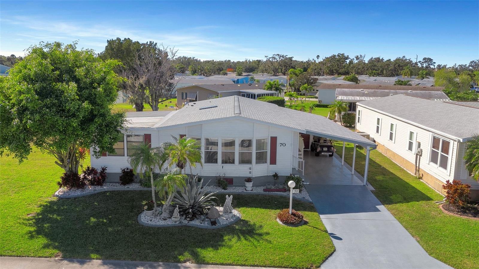 Welcome to the tranquil community of Ridgewood Oaks! NO LOT RENT! Nestled amongst this lovely 55+ community is this meticulously maintained 2 bed, 2 bath home complete with air conditioned Florida room, covered parking, outside shop (also air-conditioned), screened patio and concrete grilling area.  Upon arriving at the home you will notice the oversized lot that is situated immediately beside the guest parking, making it incredibly convenient for any guests you may have visiting.  This move-in ready home comes with most furnishings and includes: NEW roof (2025), updated water heater (2023) and A/C (2021), manicured landscaping and hardscaping, NEW washer & dryer (2025), shower and tubs resurfaced (2025) and all kitchen appliances. Those who love to cook will appreciate the functional layout of the kitchen with a built-in wall oven, center island with cooktop as well as a spacious pantry.  The home features numerous windows throughout that bathe the interior in natural Florida sunshine.  Being close to the community center you will be able to enjoy all of the amenities that Ridgewood Oaks has to offer including clubhouse, pool, spa, tennis courts, pickleball courts, shuffleboard and outdoor fitness area.  Low HOA and Condo fees include: 24 hour manned and gated security, cable, internet (spectrum), trash, yard waste, irrigation as well as maintenance of common areas and all of the previously mentioned amenities.  Commutes are a breeze with I-75, Ellenton outlet mall and multiple dining options all within 1.5 miles from your front door.  Call for your private showing today!