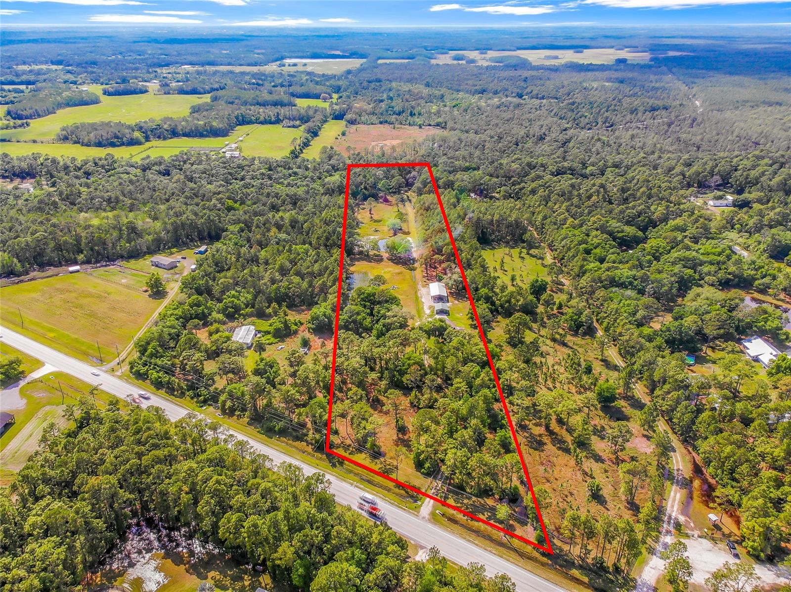Equestrian and County living friendly and short drive to the beach!  Stop looking! You found that perfect Log Cabin, situated on 10 beautiful acres with a pond and mixture of improved pasture, planted pines and majestic oak trees.  As you approach this home, you are welcomed with a large elevated wraparound/covered deck (31’ x 14’) that creates great outdoor space for cooking, entertaining guests, watching the “backyard” deer/turkey play and for enjoying your personalized sunsets! Originally designed as a 3 bedroom on the main floor , with a large loft (large enough to accommodate a home office, additional bedroom or hobby space), it is currently setup with two bedrooms on the primary floor. The Wood burning fireplace with vaulted ceilings in the living room is inviting, warm and cozy.  Heated/Cooled by 3 separate mini-split systems installed in 2021, however, additionally has a full Central heat/air system (2020) too as a backup.  New roof was installed in 2017, new kitchen and stainless steel appliances in 2018, new hot water heater and water softener system in 2018 and most windows have been replaced in 2021.  The exterior of the home was sandblasted and resealed within the past few years.  Need to see the 30’x60’ pole barn (for parking your equipment, RV, trailers), 25’x25’ metal workshop.  Even has a livestock pen.  The location of this property is a large part of its true value.  Adjacent to the 8,000+/- acre Deep Creek Preserve – which accommodates only horseback riding, hiking and bicycling.  You literally can access the preserve out of the back of your property.  Lake Ashby is approximately 5 minutes away for fresh water boating and fishing!  Approximate driving distance to New Smyrna Beach is 20 minutes.  Approximate 20 minutes to Orlando Sanford Airport and 50 minutes to the Orlando International Airport.  Also conveniently close to interstate I95 & I4 & Hwy 415 & 417.  Live in the Country, near the Beach and short driving distance to Central Florida!