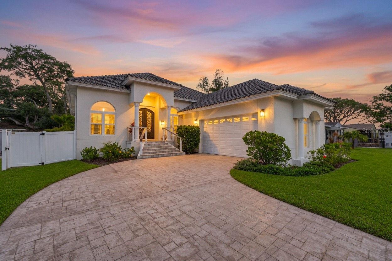 Crafted for those who appreciate exceptional design as much as flawless execution, this bespoke CUSTOM residence is a rare expression of timeless architecture, uncompromising craftsmanship, and effortless luxury. Built in 2021 with elevated all-block construction and crowned by a classic barrel tile roof, this extraordinary 4-bedroom, 2-bathroom, 2-car garage home pairs enduring quality with a refined, modern aesthetic in one of Northeast St. Petersburg's most desirable neighborhoods. A dramatic steel and wrought iron entry door introduces interiors defined by soaring 12-foot ceilings, elegant tray ceiling details, Level 5 smooth-finish walls, substantial millwork, and rich white oak engineered hardwood flooring. Bathed in natural light, the home's expansive open-concept design unfolds seamlessly, creating an atmosphere that is equally suited for intimate everyday living and sophisticated entertaining. The kitchen is a true statement in craftsmanship, anchored by floor-to-ceiling solid wood soft-close shaker cabinetry, sculptural marble countertops with a dramatic waterfall island and peninsula, a full-height marble backsplash, premium Frigidaire stainless steel appliances, a ZLINE induction cooktop, double wall ovens, microwave drawer, and designer lighting. A custom-built bar with stone countertops and a wine refrigerator further elevates the entertaining experience. Privately positioned, the owner's retreat offers a tranquil escape with elegant tray ceilings, custom built-in cabinetry, French doors opening to the terrace, a generous walk-in closet, and a spa-caliber bath featuring a freestanding soaking tub, an oversized frameless glass shower wrapped in floor-to-ceiling designer tile, dual vanities with a dedicated makeup station, and curated luxury finishes throughout. The thoughtfully designed split-bedroom floor plan provides exceptional privacy, while the guest bath continues the home's elevated aesthetic with marble surfaces, dual vanities, and floor-to-ceiling tile. Oversized sliding glass doors erase the boundary between indoors and out, opening to an expansive paver terrace enveloped by lush tropical landscaping, premium turf, fresh privacy fencing, ambient soffit lighting, and a canopy of mature palms—creating a private outdoor sanctuary designed for effortless entertaining and year-round enjoyment. Every element reflects a commitment to lasting quality, from the elevated all-block construction, hurricane protection, and oversized two-car garage to the dedicated mudroom, newer HVAC, premium Moen fixtures, Rain Bird irrigation system, Square D electrical panels, Ring security, and underground drainage. Just moments from waterfront parks, tennis courts, pickleball, soccer fields, playgrounds, and kayak and paddleboard launches, this exceptional residence offers a lifestyle where architectural beauty, enduring craftsmanship, and everyday luxury exist in perfect harmony. Call today for a private showing!