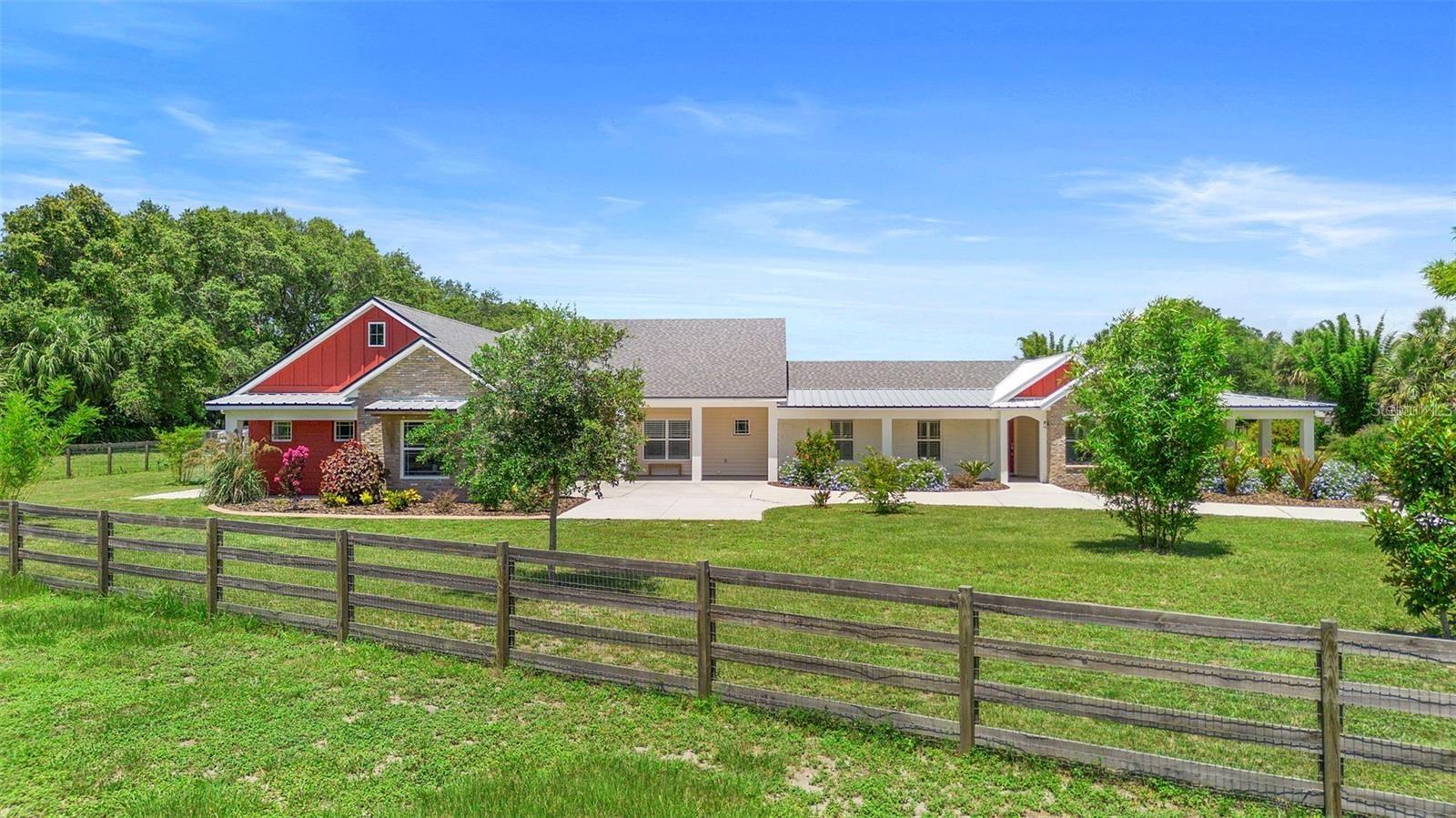 PRICE IMPROVEMENT! Discover the perfect blend of the ideal living space, privacy, and convenience with this stunning ranch-style home situated on 7.91 high-and-dry acres. Located on a paved road with no HOA, this fully fenced with no-climb horse wire property is ideal for horses, cattle, or any livestock you desire.  If you are not into livestock, bring your recreational toys! With 3313 sq. ft. of total living space, this Split Plan Plus home features two full living areas, each equipped with its own kitchen and laundry rooms, including appliances. This Split Plan Plus layout makes it an excellent choice for multigenerational living or a private retreat for extended family. There is an office space that can easily be converted into a fourth bedroom, an interior mud room-dog grooming station with a vanity and shower inside the grooming station.  A breezy wraparound porch that provides easy access to all entrances and offers a welcoming outdoor living space. Step outside to enjoy professionally landscaped gardens designed for both privacy and beauty, where you can watch rocket launches from your front yard! The property also boasts a massive 36’ x 108’ barn, complete with concrete breezeways (both center and side), two 12’ x 24’ enclosed rooms (one with an additional exterior 12’ x 24’ concrete pad). The barn roof was installed in 2019. Additionally, an 86-inch TV with a new console will convey with the home. Notable updates include: - New roof completed in fall 2023 for the entire house - A 1990 sq. ft. addition completed in late 2023 - A 1323 sq. ft. area completely remodeled - Granite countertops throughout - Waterproof luxury vinyl and tile flooring - Whole-house water processor 10/2024 - Oversized 2-car garage with a rear bay door and access door - An office/flex room that can be converted into a fourth bedroom - A large storage room under A/C and a storage room above the garage (28’ x 8’ x 6.15’) - A dog grooming room/mud room with a shower and sink, an outside kennel, and a doggy door. The entire house is connected to a new septic system (completed in late 2023). This ideal location is your personal country quiet retreat, that is only 13 minutes away from two Publix grocery stores and less than 20 minutes from Downtown Sanford's Riverwalk, Oviedo, Mims, I-95, and the 417 toll road. Launch your boat at the public boat ramp that puts you directly into the ST. John's River!! This unique property combines modern updates with rural charm and is ready for your family, pets, and lifestyle!