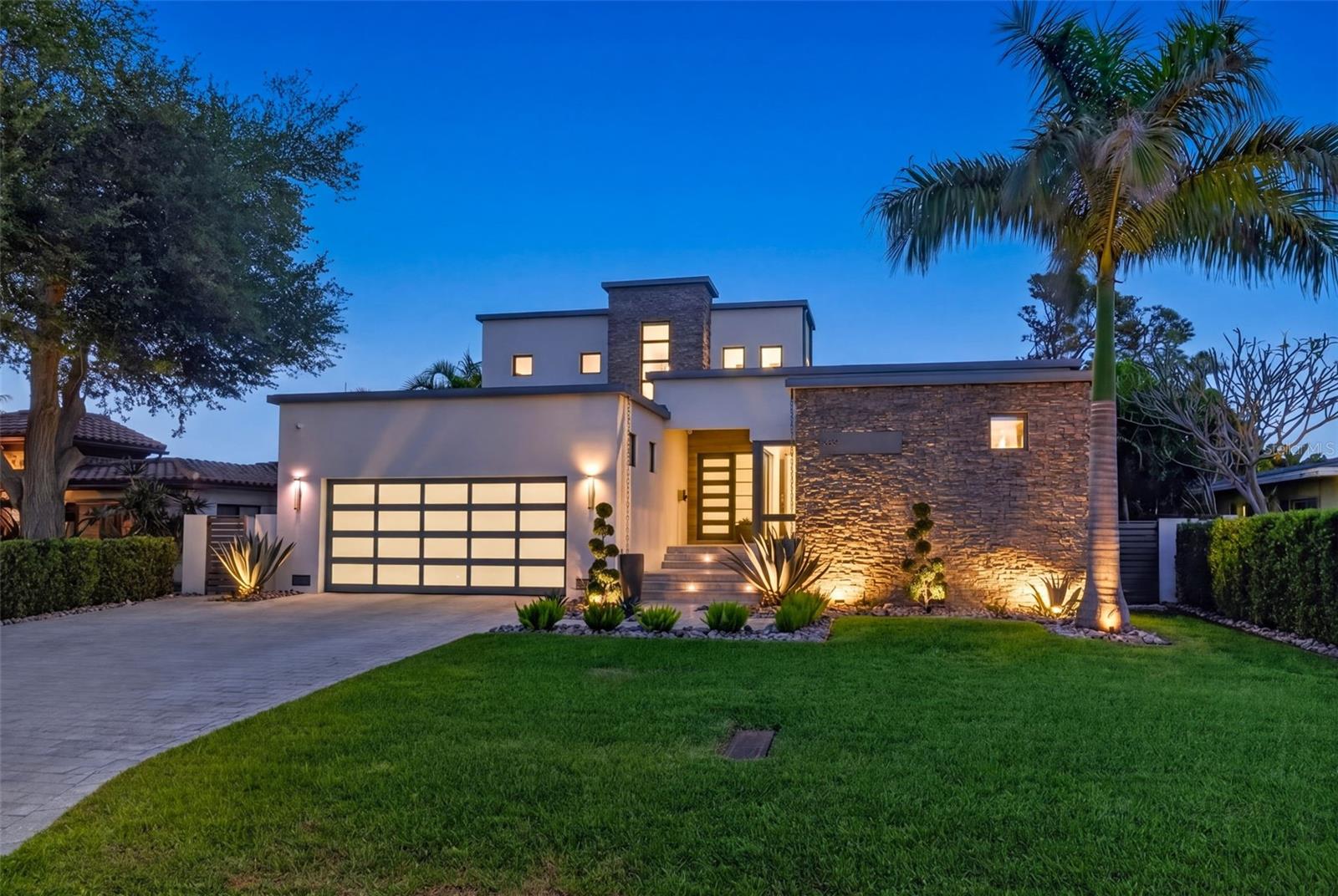 Nestled within the coveted waterfront enclave of North East Park, this extraordinary contemporary residence by Bright Bay Builders offers a masterful blend of refined architecture, cutting-edge technology, and elevated coastal living. Completed in June 2022, the custom-designed waterfront estate encompasses 3,622 square feet of impeccably curated living space with four bedrooms, four full bathrooms, an oversized two plus-car garage, expansive balconies, and seamless indoor-outdoor entertaining spaces.
Constructed with exceptional attention to durability and design, the home features a solid block foundation and two-story masonry construction built one foot above FEMA Flood Zone. The striking exterior showcases cultured stone and marble accents, while inside, oversized windows, sliding glass doors, and soaring 10-foot ceilings flood the residence with natural light and frame tranquil water views throughout.
Designed for both large-scale entertaining and effortless everyday living, the open-concept floor plan is anchored by elegant honed marble flooring and a showstopping chef’s kitchen. Outfitted with premium Wolf, Sub-Zero, and Miele appliances, the kitchen also features a 56” Galley sink, custom cabinetry, expansive prep space, a built-in bar, and a climate-controlled 216-bottle wine room.
The main-level waterfront primary suite is a private retreat offering a sitting area and direct access to a secluded patio. The spa-inspired primary bath is appointed with custom cabinetry, stone countertops, Hansgrohe fixtures, dual zero-entry walk-in showers, and a private water closet. Beyond privacy glass doors, the 184-square-foot custom dressing room delivers boutique-style luxury with abundant storage, enclosed cabinetry, oversized mirrors, built-in dresser, and a dedicated seating area.
A custom European White Oak staircase leads to the upper-level lounge, a naturally lit gathering space complete with a wet bar and Sub-Zero beverage center, creating ideal separation and privacy from the main living area. Two spacious en-suite bedrooms occupy opposite wings of the second floor, including one with a private waterfront balcony. Each suite offers oversized bathrooms with Hansgrohe fixtures and private water closets. A fourth guest suite on the main level provides flexibility as a private office or guest accommodations.
Every detail of the residence has been thoughtfully integrated with modern convenience, including smart-home system with Lutron lighting controls, motorized shades, ES Low-E impact windows and doors, whole-house generator, on-demand gas water heaters, and professionally designed landscape and pathway lighting.
Large sliding glass doors open to nearly 400 square feet of covered outdoor living space featuring a fully equipped kitchen with a built-in gas grill, large sink, and Sub-Zero refrigerator. Beyond, a resort-style saltwater pool with sun shelf and lounging areas overlooks the water, creating a true private oasis.
For boating enthusiasts, the oversized dock is equipped with a fish-cleaning station and a premium custom-maintained 10,000-pound boat lift, providing effortless access to Tampa Bay waters.
Blending masterful design, invisible technology, and an unparalleled waterfront lifestyle just moments from downtown St. Petersburg, this exceptional residence represents one of the area’s rarest contemporary offerings. Listing agent is owner.  Verify all dimensions.