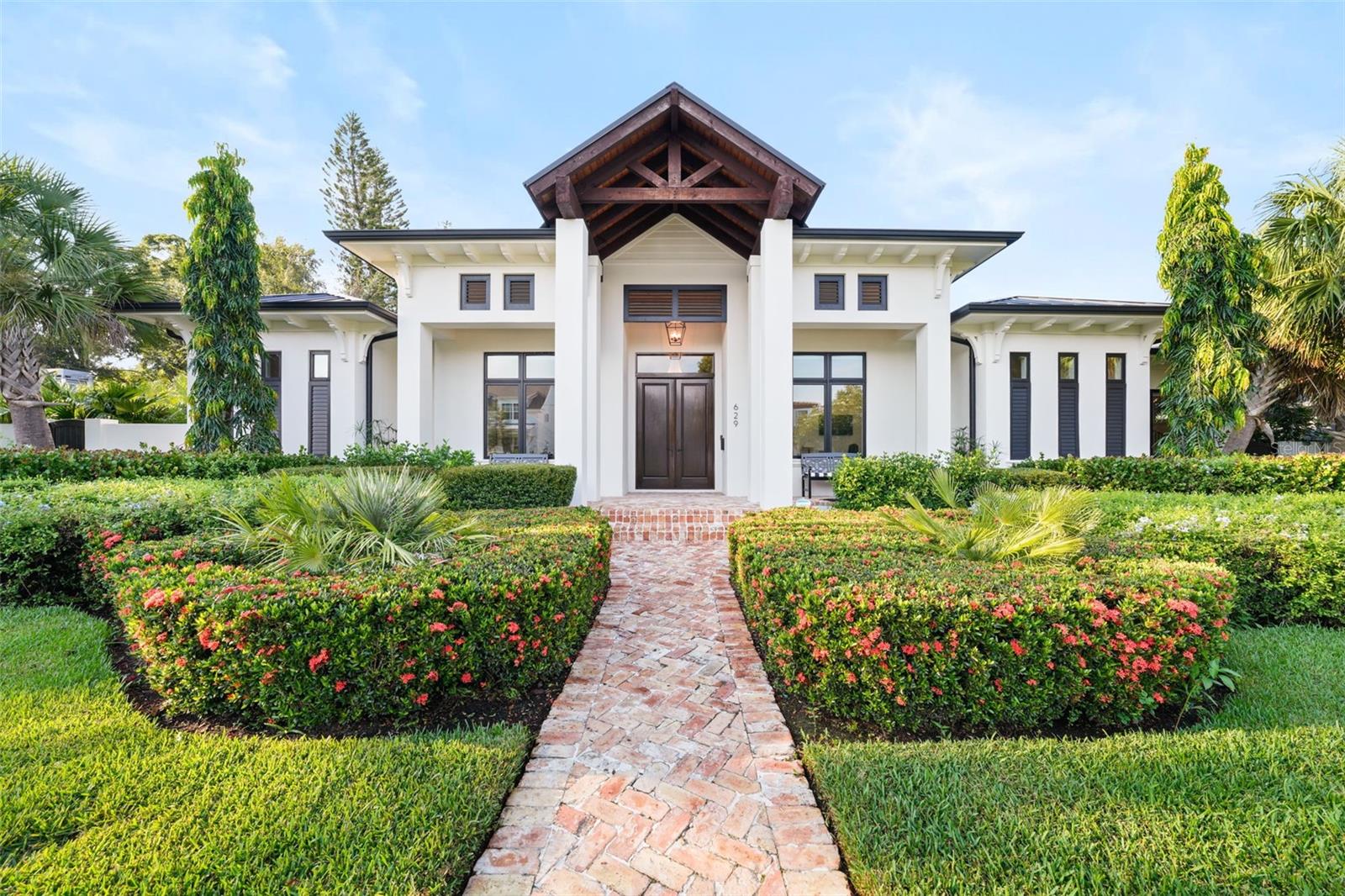 Located on a rare double lot within Flood Zone X, this 2021 custom-built residence blends timeless craftsmanship with modern comfort. From the herringbone brick walkway to the tongue-and-groove front porch, the attention to detail is evident from the start. Solid block construction and a 50-year standing seam metal roof provide lasting durability, while professionally landscaped grounds, irrigation on a private well, hurricane-impact windows, foam insulation, a whole-home generator, and a state-of-the-art security system offer peace of mind.

Inside, soaring ceilings, abundant natural light, and French doors connect seamlessly to the resort-style backyard. A dedicated office with full closet and built-in mail drop adds convenience, while the gourmet kitchen boasts a Sub-Zero refrigerator, Viking double oven, Bertazzoni gas cooktop, quartzite counters, oversized island, built-in ice maker, and walk-in pantry. The open design links kitchen, dining, and living areas, anchored by a remote-controlled gas fireplace. An additional family room with beamed ceilings, antique glass accents, and a wet bar with ice maker and dual wine fridges creates an inviting gathering space.

Outdoor living shines with a heated pool, sun shelf, spillover spa, and a covered patio with tongue-and-groove ceiling, recessed lighting, dual fans, built-in grill, pizza oven, sink, storage, and dual trash receptacles. A poolside half bath and keypad alley entry with two extra parking spaces enhance privacy. The west-wing primary suite features dual custom walk-in closets and a spa-inspired bath with zero-entry glass shower, soaking tub, double vanity with built-in hampers, and private water closet. French doors open directly to the pool, blending indoor serenity with outdoor luxury. Two guest suites in the east wing include walk-in closets and designer baths—one with soaking tub, the other with walk-in shower.

The laundry room offers a farmhouse sink, marble backsplash, soft-close cabinetry, built-in desk, and secondary refrigerator. A two-car attached garage is paired with a climate-controlled single-car garage with mini-split A/C, epoxy floors, sink, and attic space—ideal for a gym, office, or studio. Additional highlights include seamless gutters, dual attic storage, surround sound (app-controlled), blackout shades, and a whole-house water filtration system. Powered by natural gas—including fireplace, chef’s range, pool heat, dryer, and pizza oven—this home is designed for both luxury and efficiency. A northeast side yard with generator and storage is perfect for pets or extra equipment. Just minutes from the dining, shopping, museums, and waterfront parks of Downtown St. Petersburg, this home offers a rare combination of elegance, durability, and Florida’s coveted indoor-outdoor lifestyle.