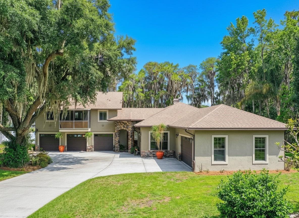 HUGE $100,000 PRICE DROP! Welcome to a truly rare lakefront estate offering the perfect blend of luxury, privacy, and breathtaking natural beauty. Set on over 12 pristine acres along the shores of a private 250-acre lake brimming with majestic cypress trees, this exceptional property captures spectacular west-facing sunset views that paint the water in golden light each evening.

Originally constructed in 1994 with the garage and original living area, the estate was expanded and beautifully reimagined in 2012 with the addition of the main home, designed to complement its natural surroundings while providing modern comfort, elegance, and architectural distinction.

Designed for refined living and effortless entertaining, the residence features 3 bedrooms plus an office and 3.5 bathrooms, thoughtfully arranged between the main home and attached guest quarters to maximize comfort, flexibility, and privacy.

Inside, the main residence showcases elegant open-concept living with soaring ceilings, abundant natural light, and a seamless connection between indoors and outdoors. At its heart lies a chef’s kitchen—complete with a massive center island, premium cabinetry, stone countertops, and professional-grade appliances—flowing into expansive living and dining areas framed by sliding glass doors. Step onto the screened lanai to enjoy peaceful lake views, gentle breezes, and direct access to your private dock—the perfect spot for morning coffee or golden-hour sunsets.

The primary suite serves as a serene retreat, featuring its own sitting area or office nook and panoramic water views framed by the cypress-lined shoreline. The spa-inspired bath offers a soaking tub, walk-in shower, dual vanities, and dual walk-in closets.

Ideal for guests or multi-generational living, the attached guest wing includes two spacious bedrooms, a full bath, and a private lakeview balcony—all with the same high ceilings and light-filled openness as the main residence.

Outdoors, the landscape flourishes with fruit trees and lush greenery, creating a tranquil and productive environment. The estate features avocado and mango trees, a peach tree, nectarine, navel orange, lemon, two persimmon trees, two Barbados cherry trees, kumquat, olive trees, and a pomelo—a vibrant orchard oasis that embodies the best of Florida’s natural abundance.

For collectors, hobbyists, and outdoor enthusiasts, the property offers exceptional amenities: a five-car attached garage, a detached air-conditioned barn/garage, a 40 foot RV shelter, and an additional oversized carport. Every element balances elegant design and practical versatility.

Blending luxurious finishes, expansive acreage, a cypress-lined 250-acre lake, a flourishing orchard, and unforgettable sunsets, this one-of-a-kind property stands as a true private sanctuary, seamlessly uniting nature, craftsmanship, and timeless style.