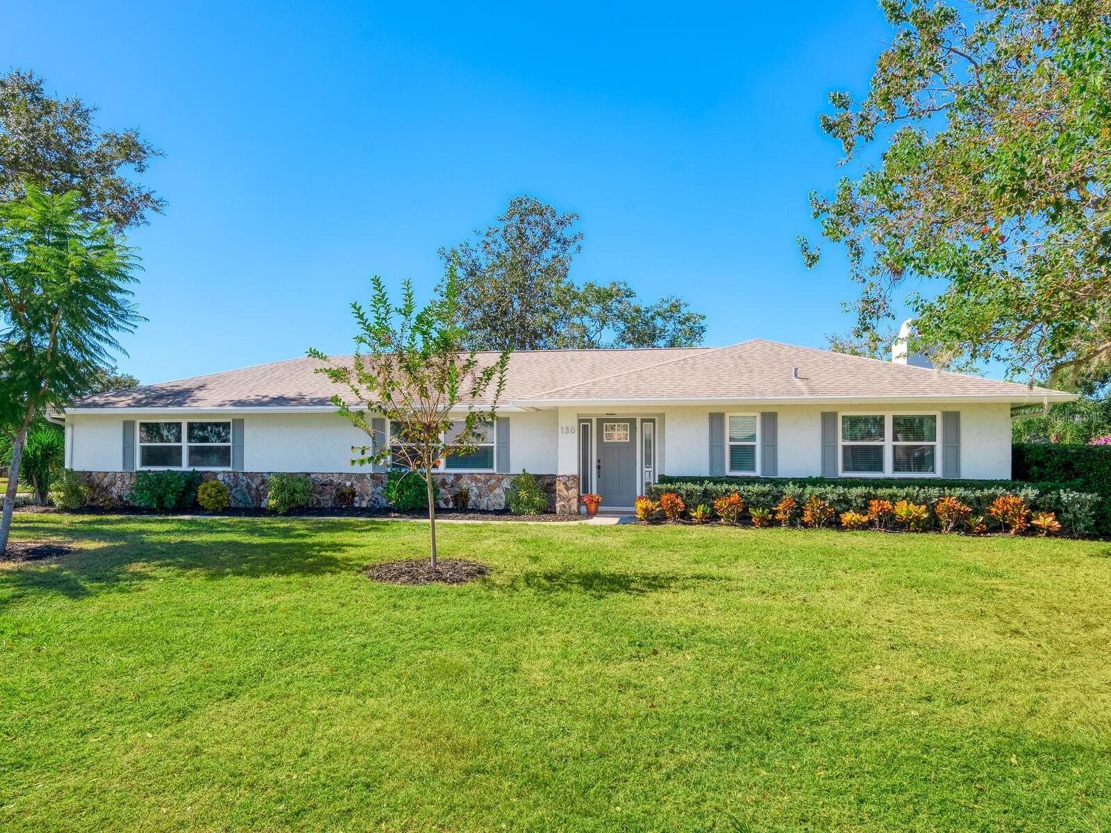 Virtually Staged. Set on a quarter-acre corner lot within a deed-restricted Sarasota community, this four-bedroom, two-bath residence blends comfort with modern enhancements. Constructed with concrete block and new hurricane-impact windows and doors, the home offers peace of mind and long-term value. The split floor plan delivers privacy and function, with primary suite positioned at the north end. The updated primary bath and expansive walk-in closet provide a refined retreat. At heart of the home, the open-concept kitchen showcases granite countertops, soft-close cabinetry, and bar seating that opens to a large dining area and vaulted family room with lake views and a travertine-clad wood-burning fireplace. Travertine and wood flooring extend throughout. Three-panel sliding doors reveal a screened lanai ideal for entertaining, offering serene lake views and a fountain feature. Additional highlights include 2025 hurricane-rated garage door, a 2019 air-conditioning system, new ductwork, and an oversized two-car garage with storage. The exterior has been transformed into a private oasis, complete with upgraded landscaping and paver patio designed for Florida living. This meticulously maintained home provides a rare combination of style, structure, and setting, all minutes from downtown Sarasota and the gulf beaches.