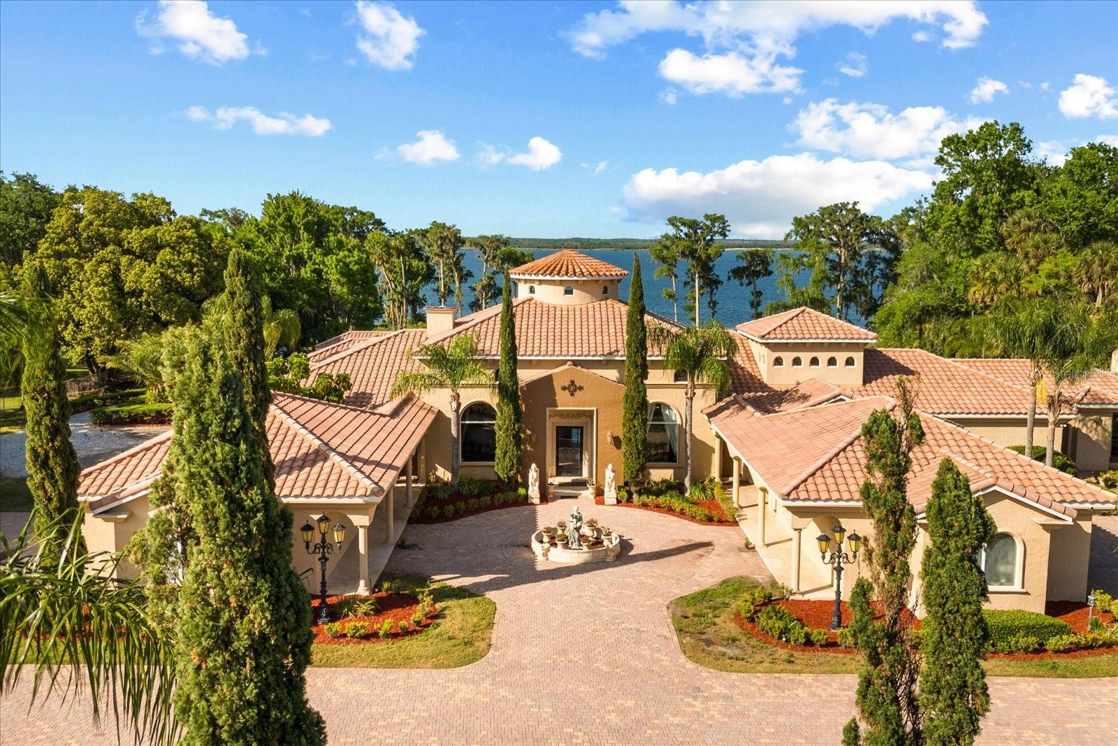 Opportunities like this are almost impossible to find in Central Florida. Situated on 5.33 pristine lakefront acres with no HOA, this extraordinary estate is commercially zoned, creating a unique opportunity for a variety of potential business uses, including a luxury wedding venue, private event space, corporate retreat, boutique hospitality concept, or an exceptional live-work estate. With its breathtaking setting, grand architecture, and resort-style amenities, the property offers a level of versatility rarely available in today's market.

Inspired by the elegance of the Italian countryside, the residence makes a lasting first impression with a dramatic front waterscape, lush gardens, and timeless architectural details. Inside, guests are welcomed by a grand foyer featuring exquisite marble finishes and a spectacular custom-painted 24-karat gold dome.

Designed for both entertaining and everyday luxury, the expansive living spaces showcase panoramic views of beautiful Lake Jessup, soaring ceilings, stunning chandeliers, and a grand marble fireplace. The thoughtfully designed "H" floor plan encompasses more than 8,000 square feet of air-conditioned living space, offering five spacious bedrooms and six-and-a-half bathrooms, all conveniently situated on a single level.
The primary suite is a true private retreat, featuring eight sets of French doors opening directly to the pool and lakefront, a custom-designed closet that doubles as a safe room, and a spa-inspired bathroom complete with a tranquil garden retreat. The gourmet chef's kitchen is equipped with top-of-the-line appliances, custom cabinetry, and an oversized walk-in butler's pantry designed to accommodate large-scale entertaining.

Additional luxury amenities include a temperature-controlled wine cellar, private movie theater, dedicated nanny or guest quarters, and a six-car garage with extensive attic storage.

Outside, the estate transforms into a private resort. A spectacular sports pool with multiple water features serves as the centerpiece, complemented by a summer kitchen, wet bar, outdoor fireplace, and expansive covered veranda overlooking the serene waters of Lake Jessup. Whether hosting elegant weddings, unforgettable events, corporate gatherings, or private family celebrations, the setting is simply unmatched.
Combining custom craftsmanship, Tuscan and Greek-inspired design elements, commercial zoning flexibility, and an irreplaceable waterfront location, this remarkable estate offers a truly rare opportunity to own one of Central Florida's most unique properties. Schedule your private tour today to experience the endless possibilities and extraordinary lifestyle this one-of-a-kind property provides.