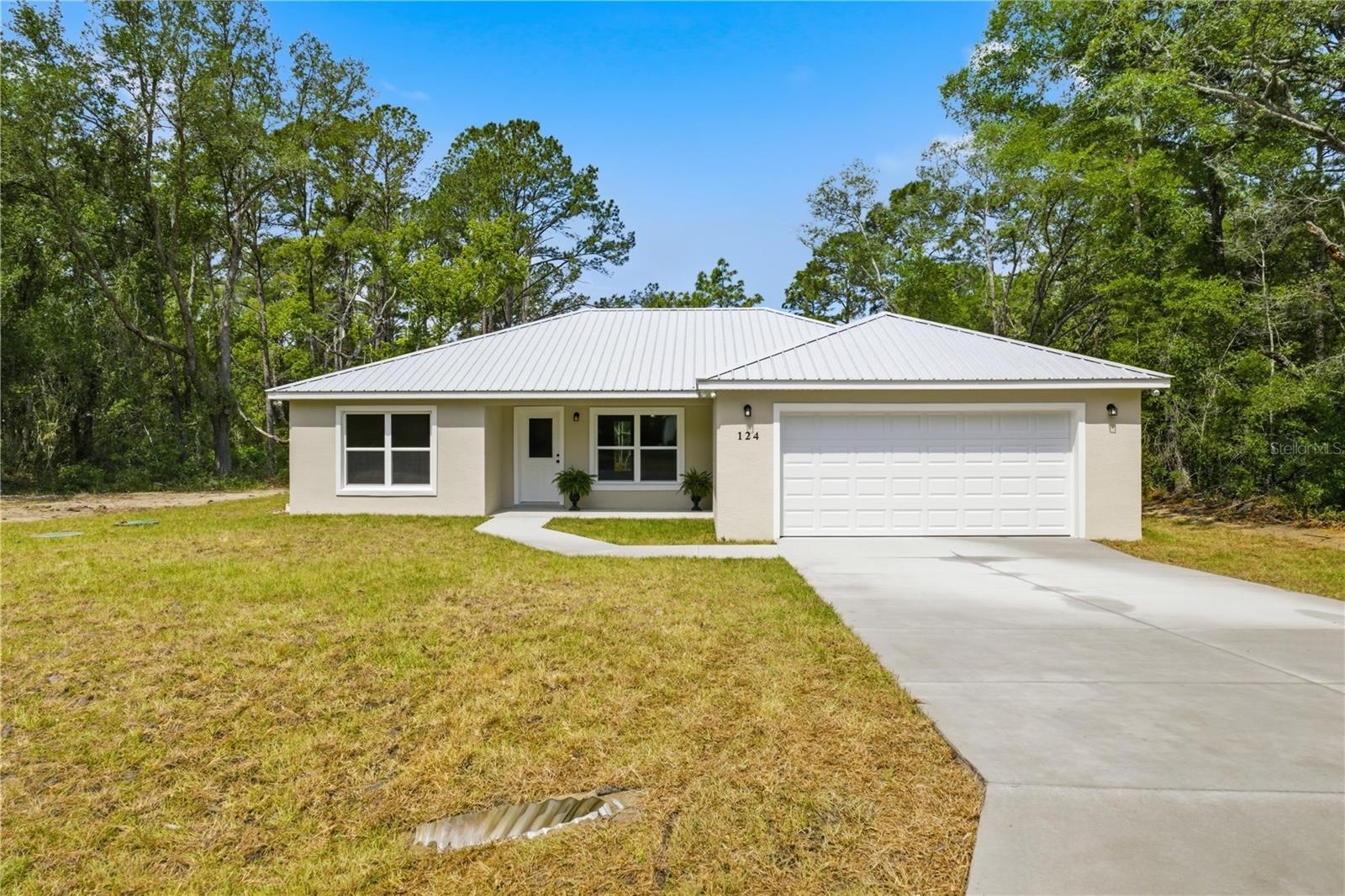 Welcome to 124 Guava Terrace in Ocklawaha — a beautifully crafted brand-new construction home designed with modern style, durability, and energy efficiency in mind. Situated on a spacious homesite surrounded by peaceful natural scenery, this move-in ready property offers the perfect blend of luxury finishes, open-concept living, and quality craftsmanship throughout.
From the moment you arrive, you’ll notice the attractive curb appeal highlighted by a durable metal roof, oversized driveway, oversized garage, and water- and weather-resistant exterior finishes built for long-lasting Florida living. Step inside to soaring vaulted ceilings, abundant natural light, recessed LED lighting, and premium LVP glue-down flooring that flows seamlessly throughout the home.
The spacious open floor plan is ideal for entertaining and everyday living, featuring a large living and dining area that opens into the stunning chef-inspired kitchen. The kitchen showcases shaker-style cabinetry, granite countertops, stainless steel appliances, designer pendant lighting, a large center island, and ample storage and prep space.
The private owner’s suite offers a luxurious retreat with oversized windows, ceiling fan, spacious walk-in closet, and a spa-style ensuite bathroom featuring dual granite vanities and an elegant porcelain tile walk-in shower. Guest bathrooms are equally well-appointed with solid surface countertops and upgraded finishes.
Built with comfort and efficiency in mind, the home features foamed attic insulation in the living area for enhanced energy savings and year-round comfort, along with pre-wiring for cable and high-speed internet. Additional highlights include porcelain tile showers, covered back porch perfect for relaxing or entertaining, and approximately 110+/- sq. ft. of decked attic storage above the garage for added convenience.
This home also includes a brand-new ATU septic and drainfield system, offering modern functionality and peace of mind for years to come.
Conveniently located near Lake Weir, Ocala, The Villages, Silver Springs, shopping, dining, outdoor recreation, boating, and fishing, this property is ideal for first-time buyers, families, investors, or anyone seeking a modern Florida lifestyle in a peaceful setting.
