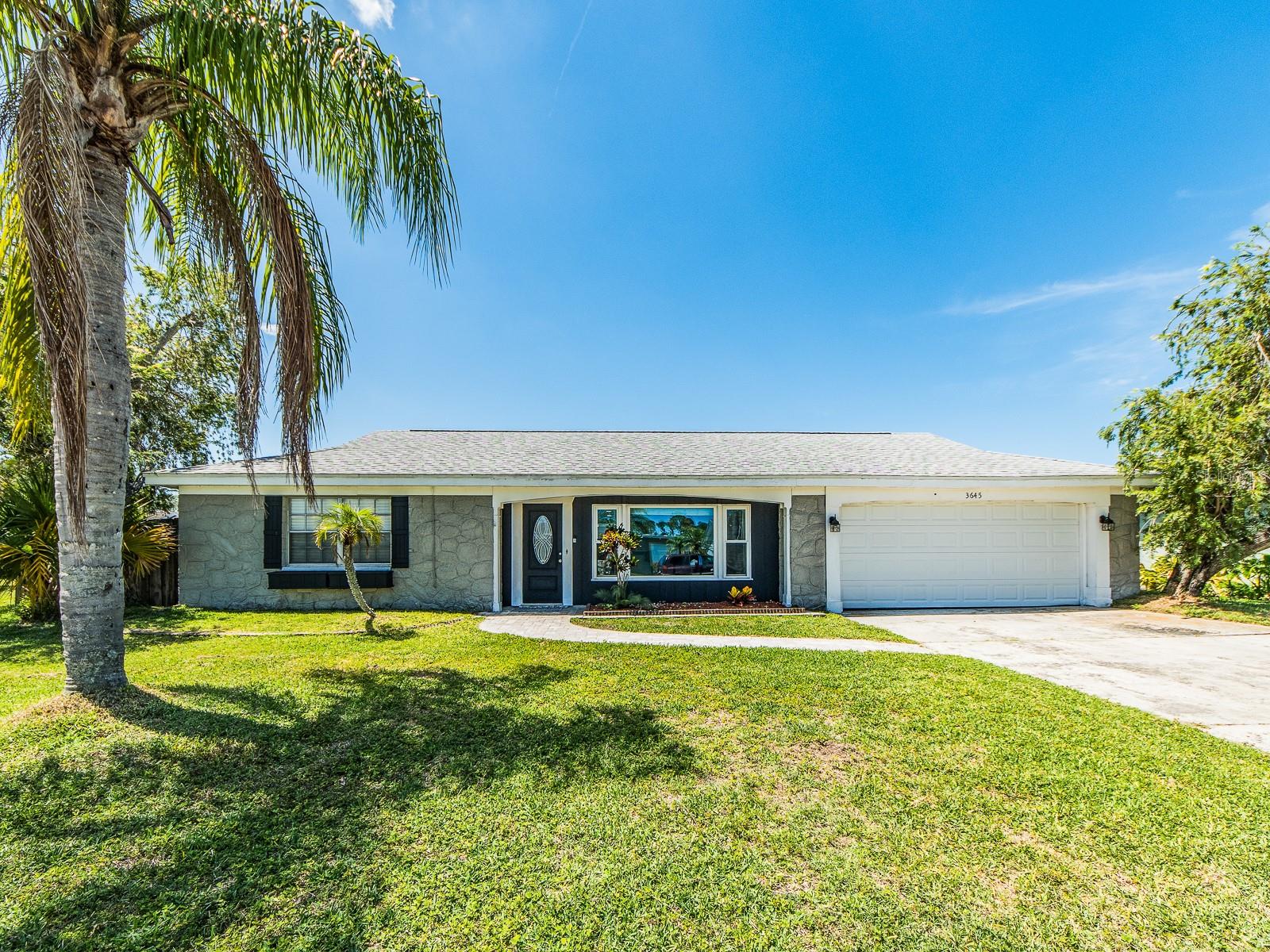 Newly renovated 3 bedroom 3 bathroom home sitting on a oversized fenced in lot with a oversized private pool. Newly added recessed lighting gives the house a warm and welcoming feel. Full bar inside home with quartz counters, mini fridge, sink and extra seating for entertaining. The waterproof wood plank flooring is a great addition for easy cleaning and protection from coming in and out from the pool area. Home has 5 sets of doors leading to pool area provide stunning views of the pool from nearly every room, effectively bringing the outdoors in.  There is no HOA or CDD. Heated and jetted tub in one of the bathrooms. Quartz countertops in the kitchen and bar area with wood cabinets and stainless appliances. The oversized lot offers ample space for family and pets to play hours on end or room for additional outdoor features. A pool of this size and features including pavers and pool cage could be quite expensive to build these days so this home is a true value! The kitchen has been completely updated with stainless steel appliances. Home also has an oversized garage for your cars and toys.This home is centrally located near boat ramps, numerous parks, popular restaurants, shops, beaches, Tarpon Springs' famous sponge docks, and Tampa Airport.