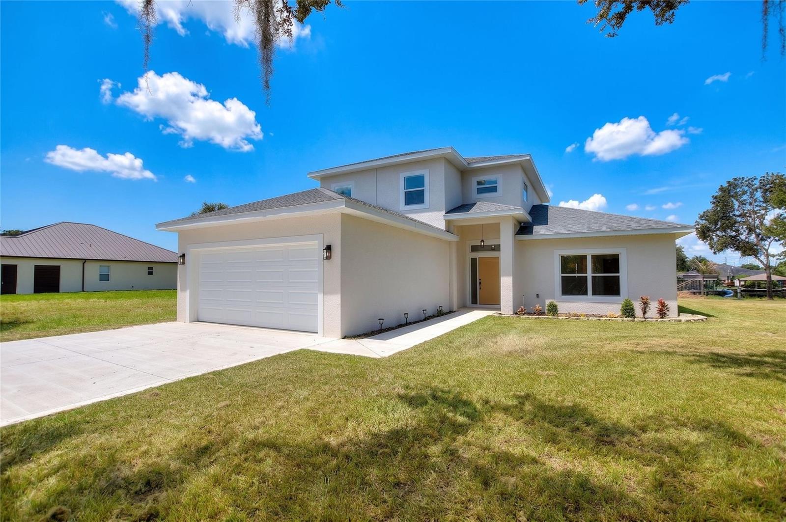 *LISTED UNDER APPRAISAL!* Welcome to your brand-new construction waterfront dream home in Lake Placid, Florida. This spectacular property perfectly blends modern farmhouse elegance with premier canal-front living to offer the ultimate Florida lifestyle. From the moment you arrive, the striking contemporary front elevation, pristine concrete driveway, and oversized two-car garage deliver a powerful first impression. The direct overhead drone perspective highlights the thoughtful footprint of the home, situated beautifully on an expansive cleared lot with an immaculate new roof.

Step through the custom front entry into a soaring, light-filled sanctuary designed for effortless open-concept living. The heart of the home features a dramatic two-story great room, beautifully framed by premium light oak-look flooring, crisp neutral tones, and high-set architectural windows that flood the entire space with natural light. Look up to admire the elegant second-story loft overlook. The seamless indoor flow connects the grand living area directly to your dining space and a gourmet chef’s kitchen. This sparkling kitchen is a masterpiece of form and function, boasting custom white shaker cabinetry with matte black hardware, a vast entertainment island topped with gleaming quartz, premium stainless steel appliances, and dual rustic-modern industrial cage pendant lights.

Pass through the massive sliding glass doors in the great room to experience true backyard paradise and direct water access. You can relax in the shade under your expansive covered lanai, complete with an outdoor ceiling fan, as you look down the peaceful waterway. The sweeping property lines show off a vast, open backyard with endless space for a custom pool, garden, or private dock. Bring your boat, jet skis, and fishing gear, because the incredible aerial overviews reveal an exceptional location on a wide, deep canal just moments away from the wide-open waters of the lake. Every square inch of this magnificent home exudes quality, cohesion, and style, making it the perfect waterfront retreat for its very first owners.